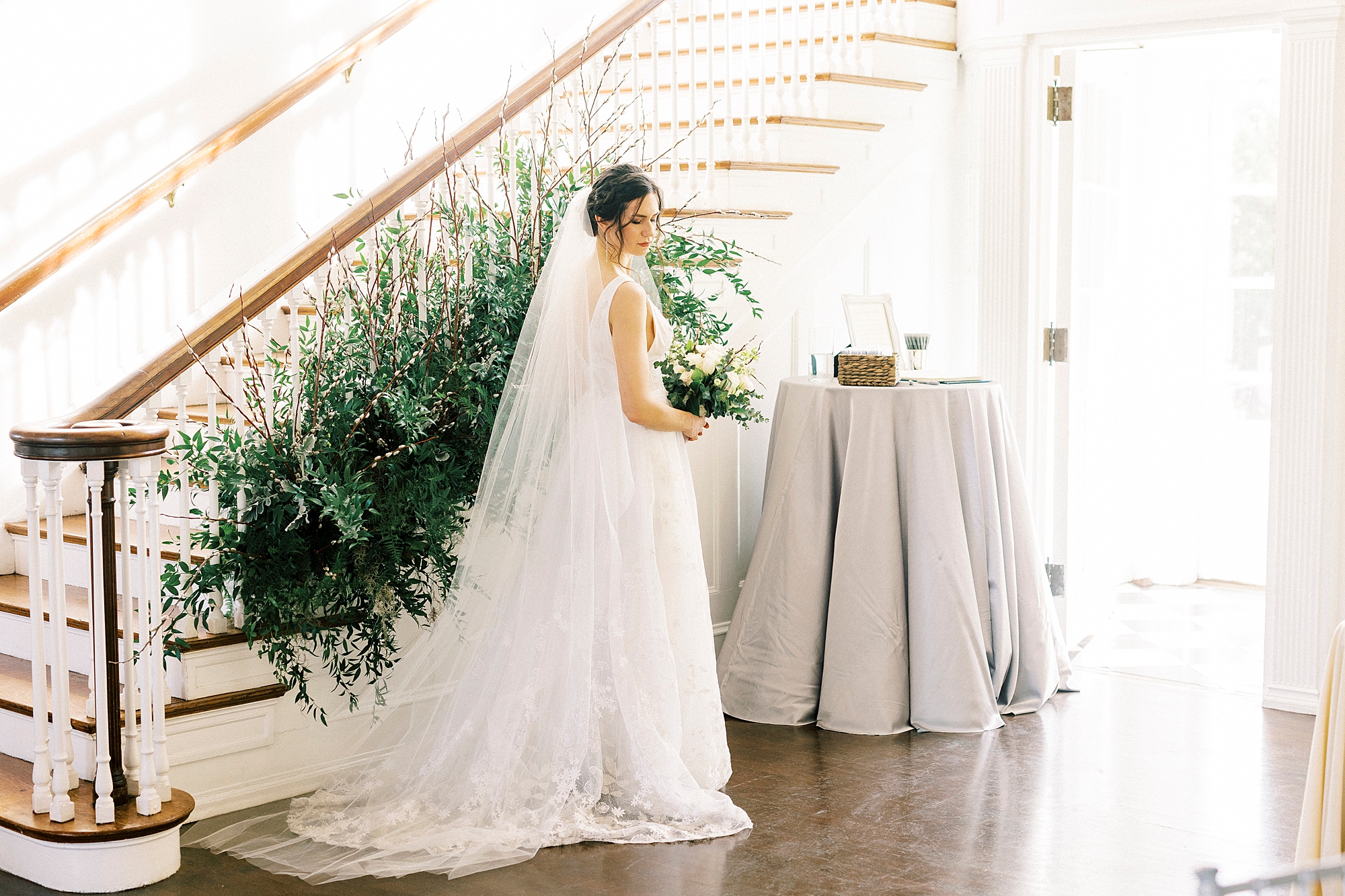 bride stands by staircase in Separk Mansion looking over shoulder 