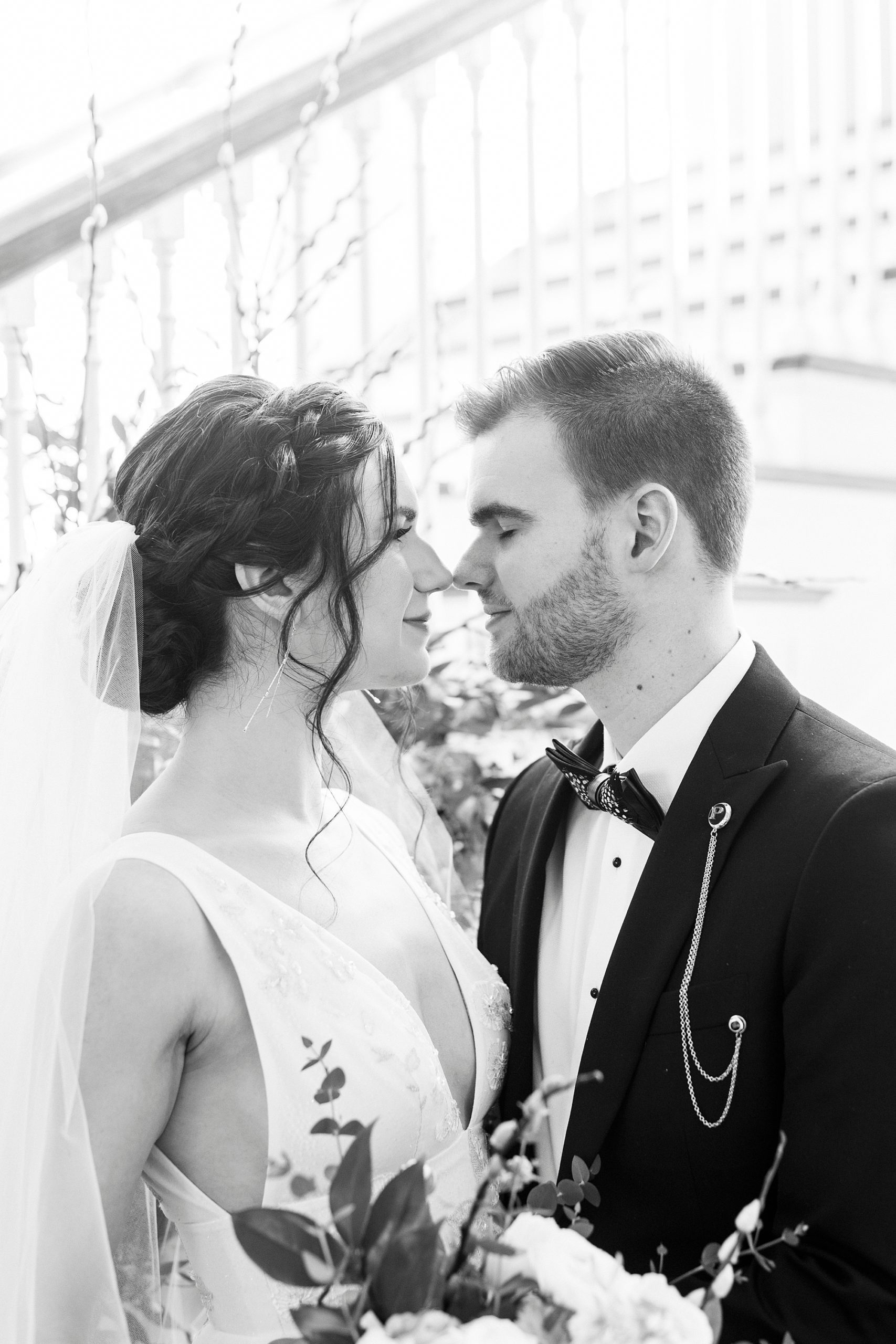 black and white portrait of bride and groom leaning to touch noses by staircase at Separk Mansion
