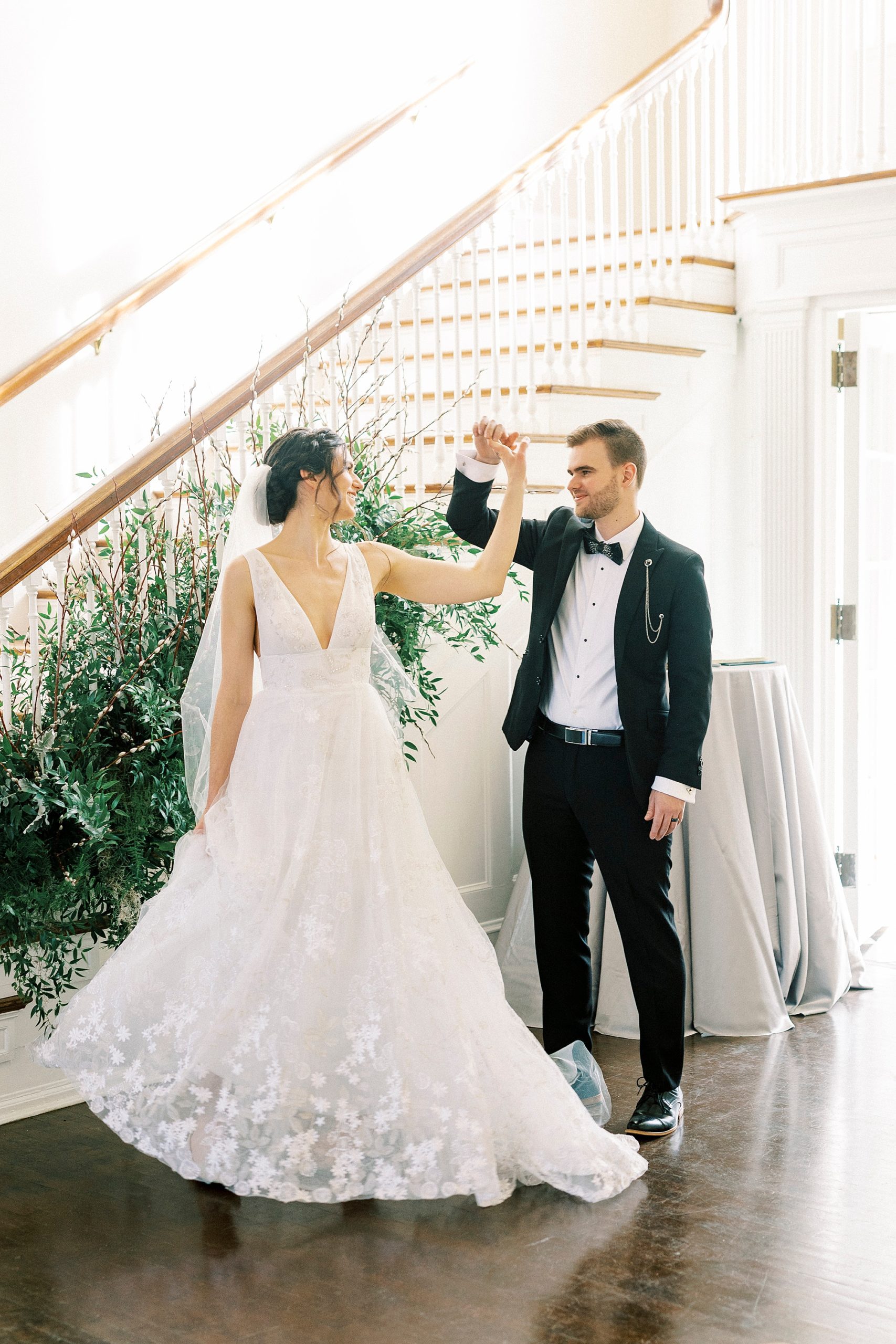 groom twirls bride by staircase at Separk Mansion