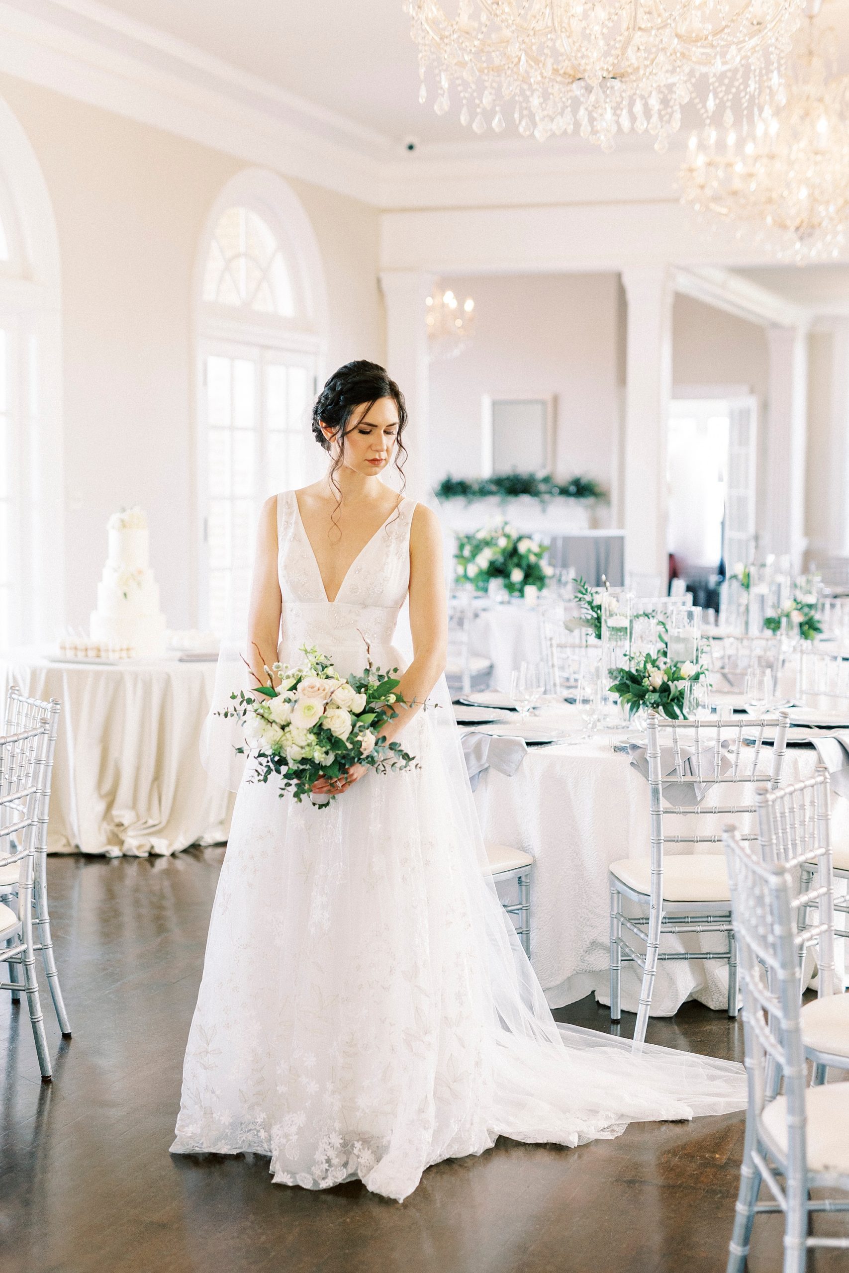 bride holds bouquet in front of her looking over shoulder 