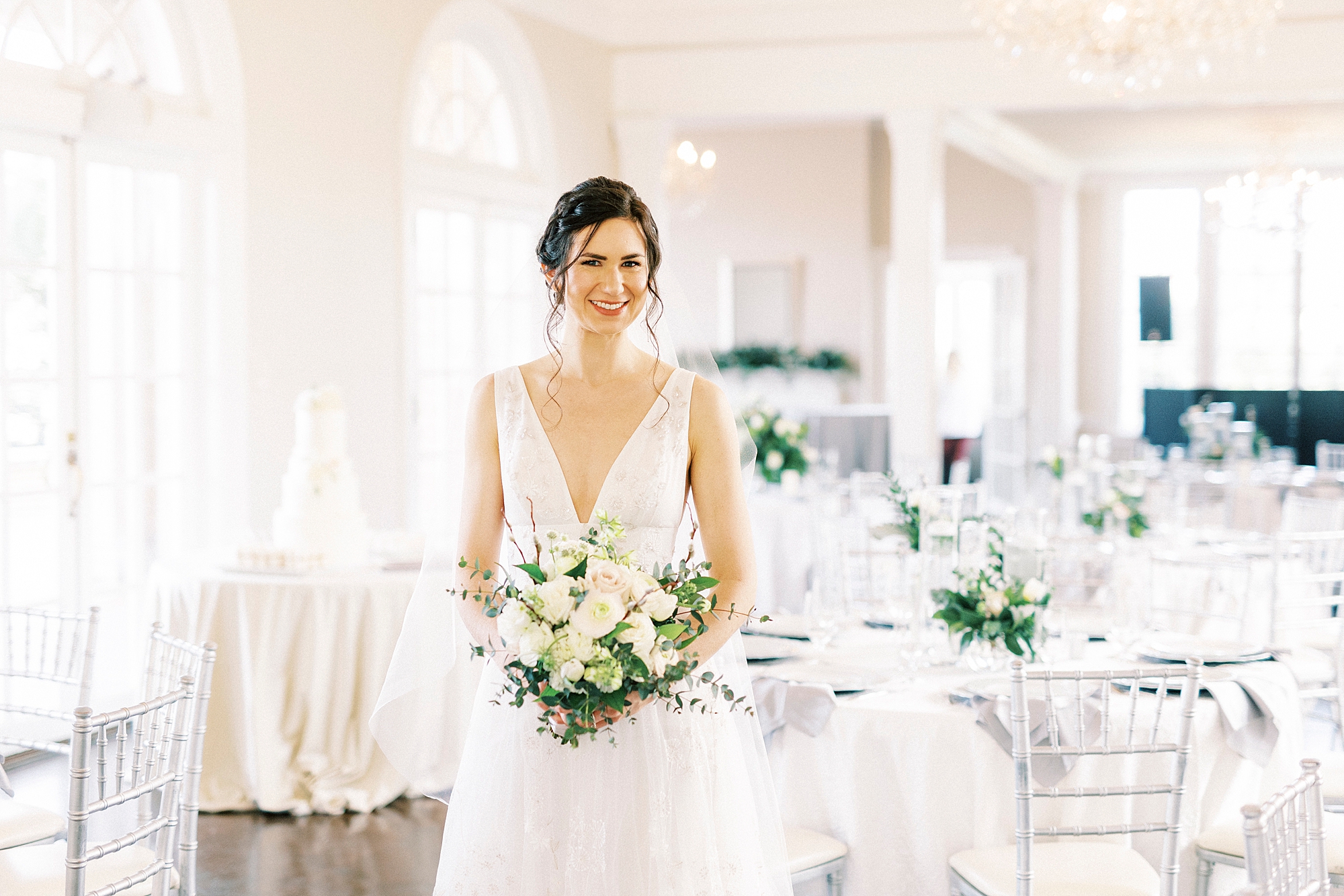 bride smiles standing in reception hall at Separk Mansion with silver chivari chairs 