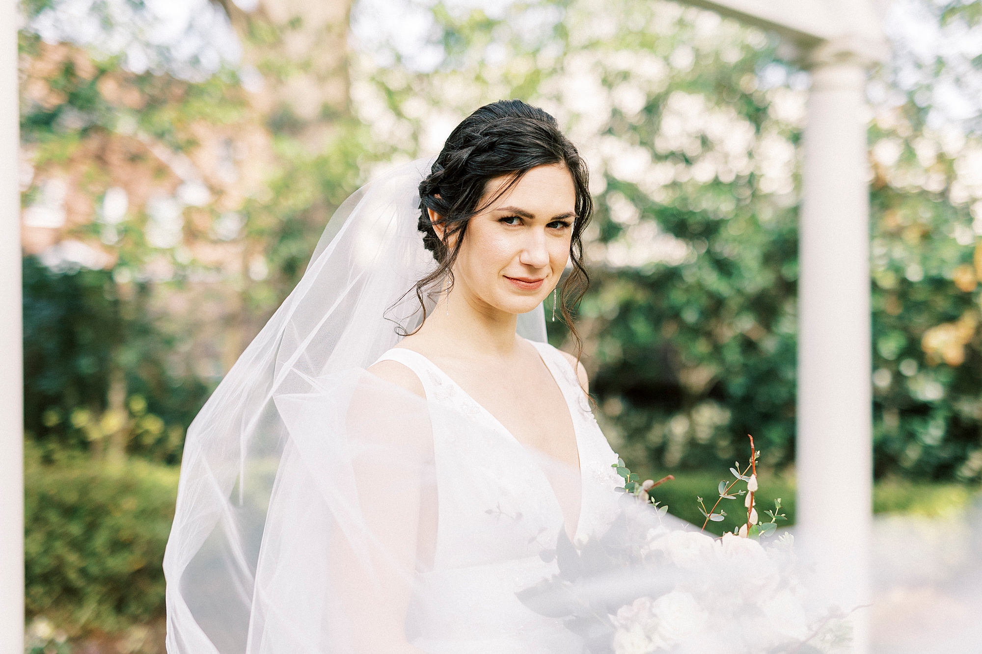 bride smiles with veil around her under arbor at Separk Mansion