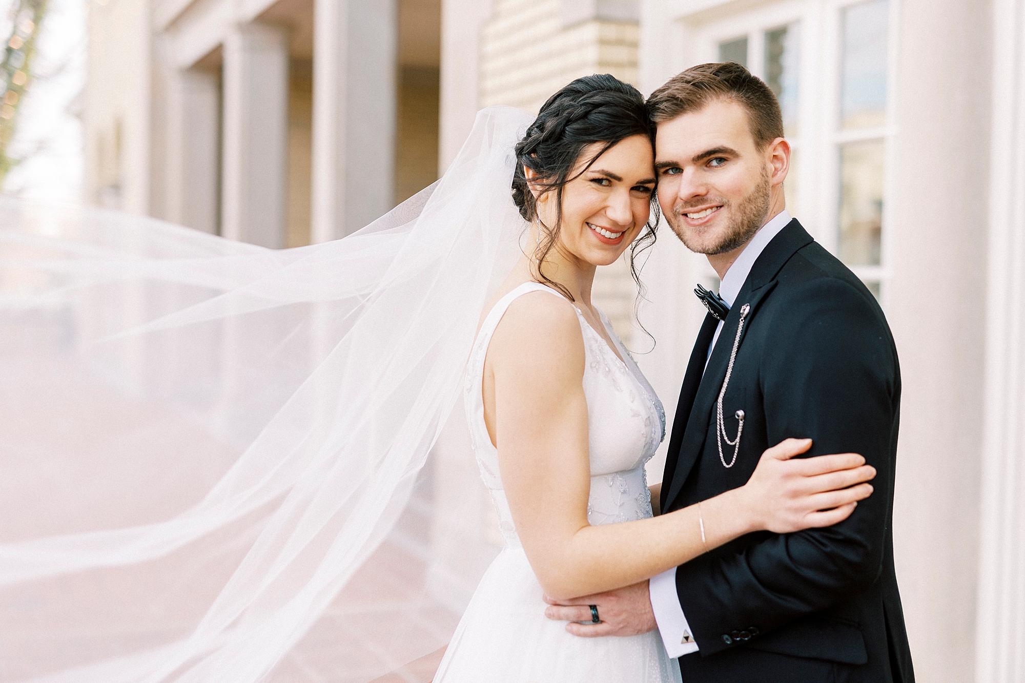 newlyweds hug while bride's veil floats behind them on patio at Separk Mansion
