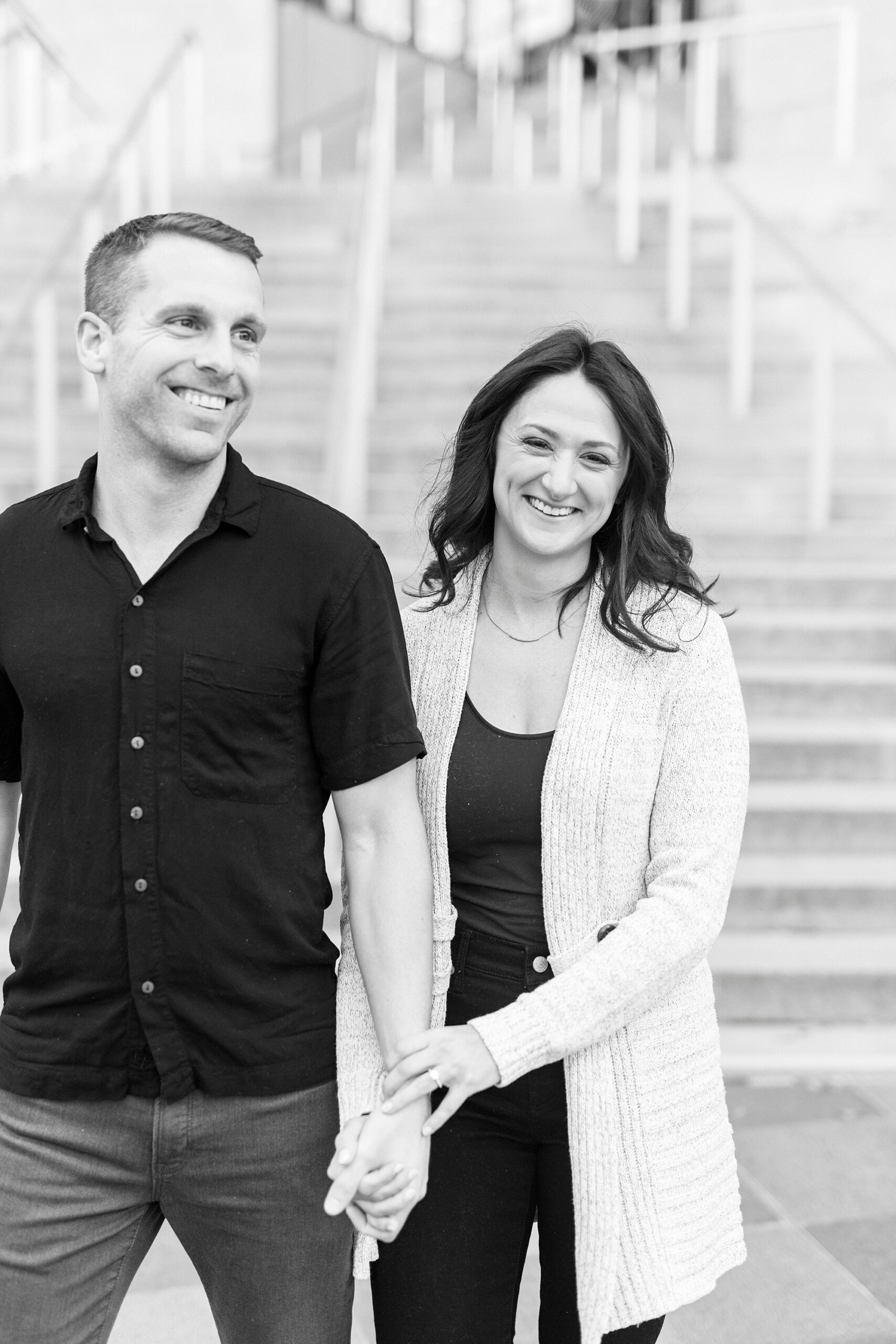 couple holds hands by staircase outside The Mint Museum in Charlotte NC