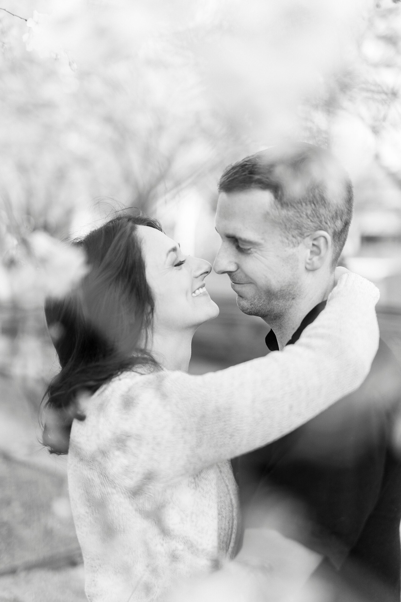 woman hugs man between trees outside The Mint Museum