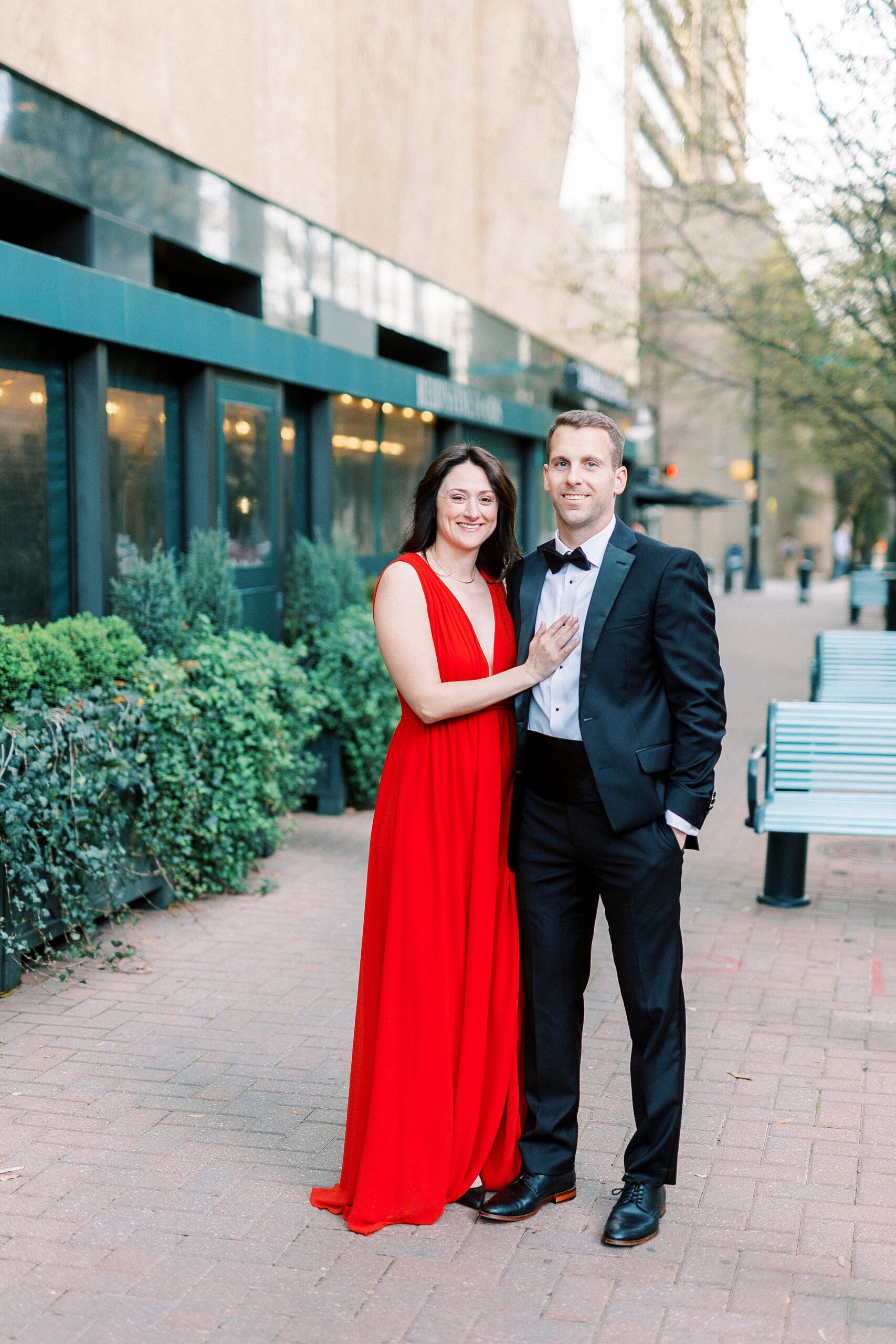 woman in red dress holds man's arm on sidewalk in uptown Charlotte NC