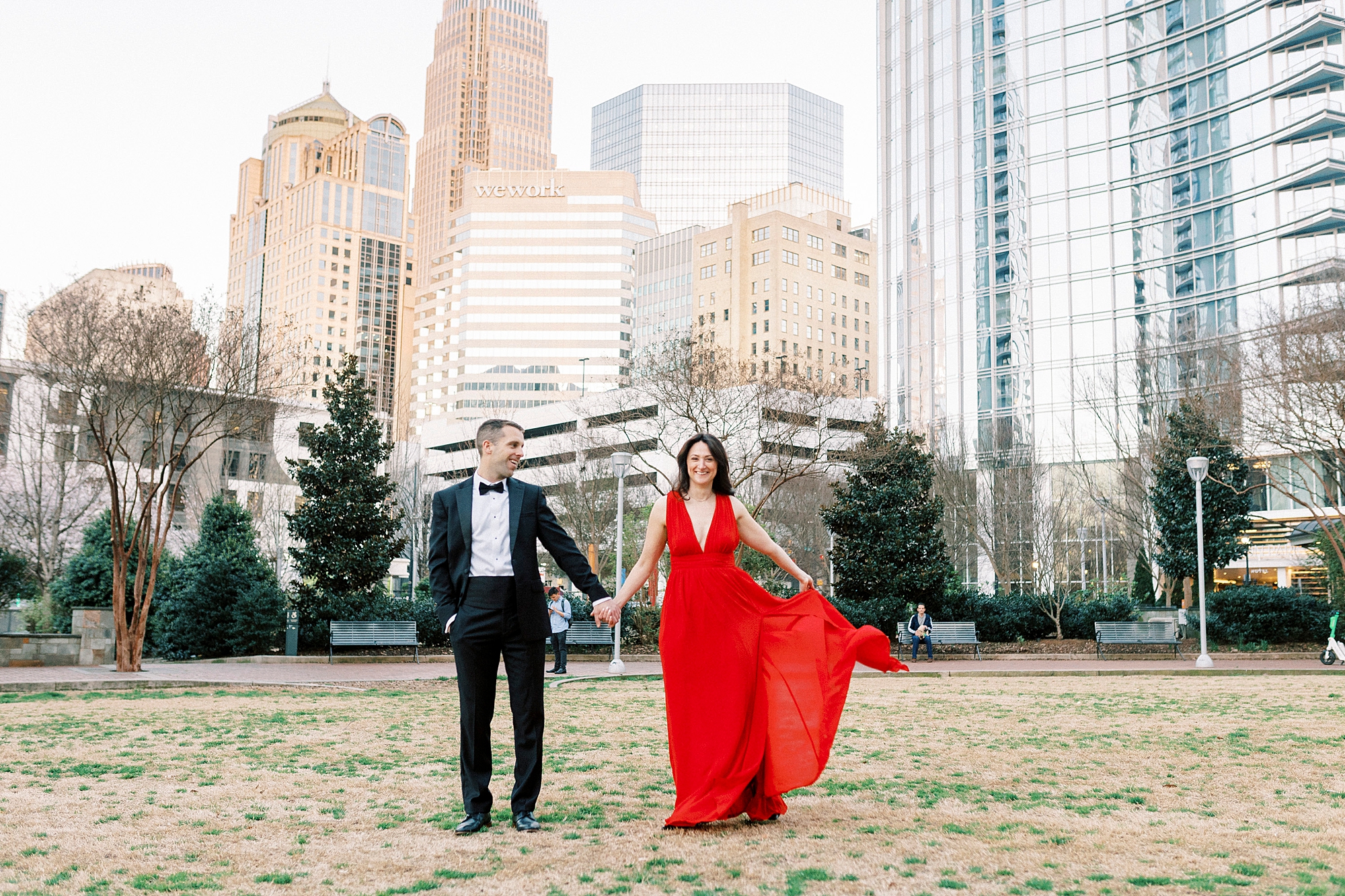woman in red dress holds out skirt walking through park in Charlotte NC