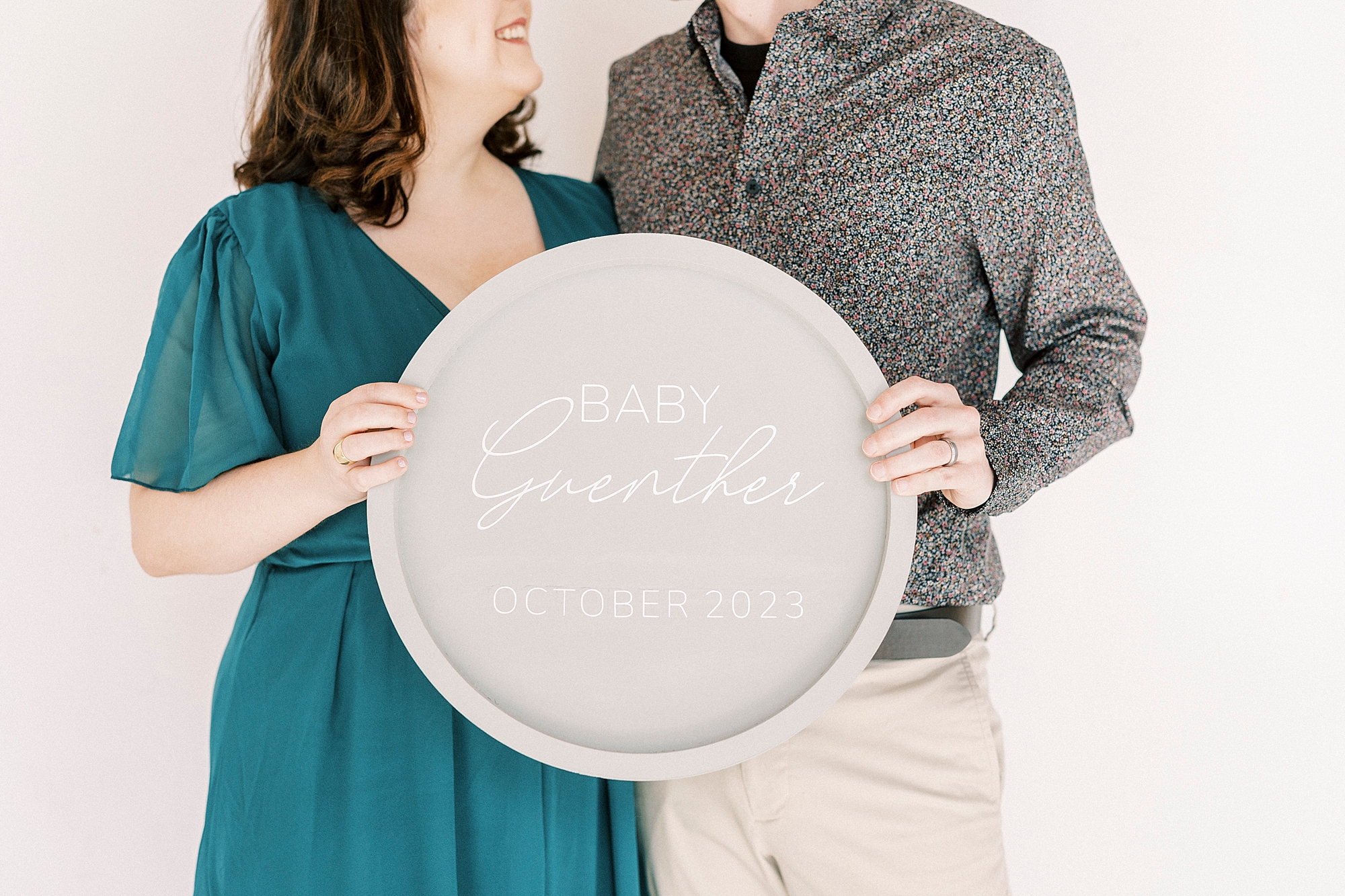 couple holds sign announcing baby