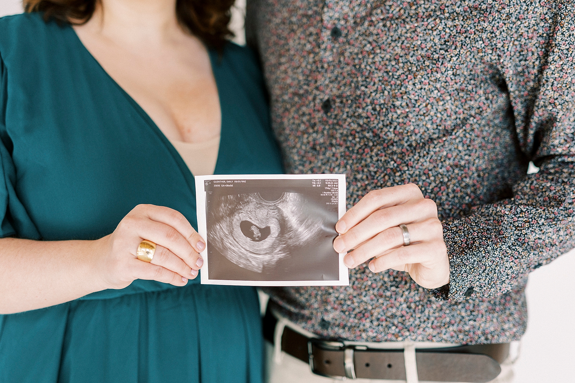 husband and wife hug holding baby's sonogram during studio pregnancy announcement in Concord NC