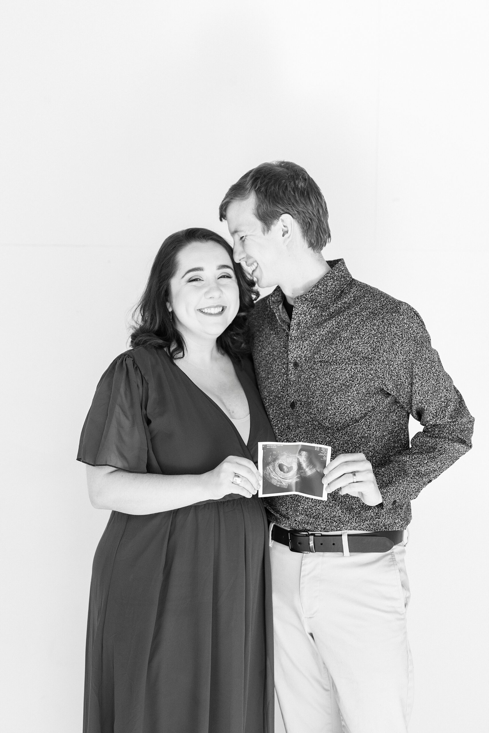 husband nuzzles wife's head during studio pregnancy announcement in Concord NC