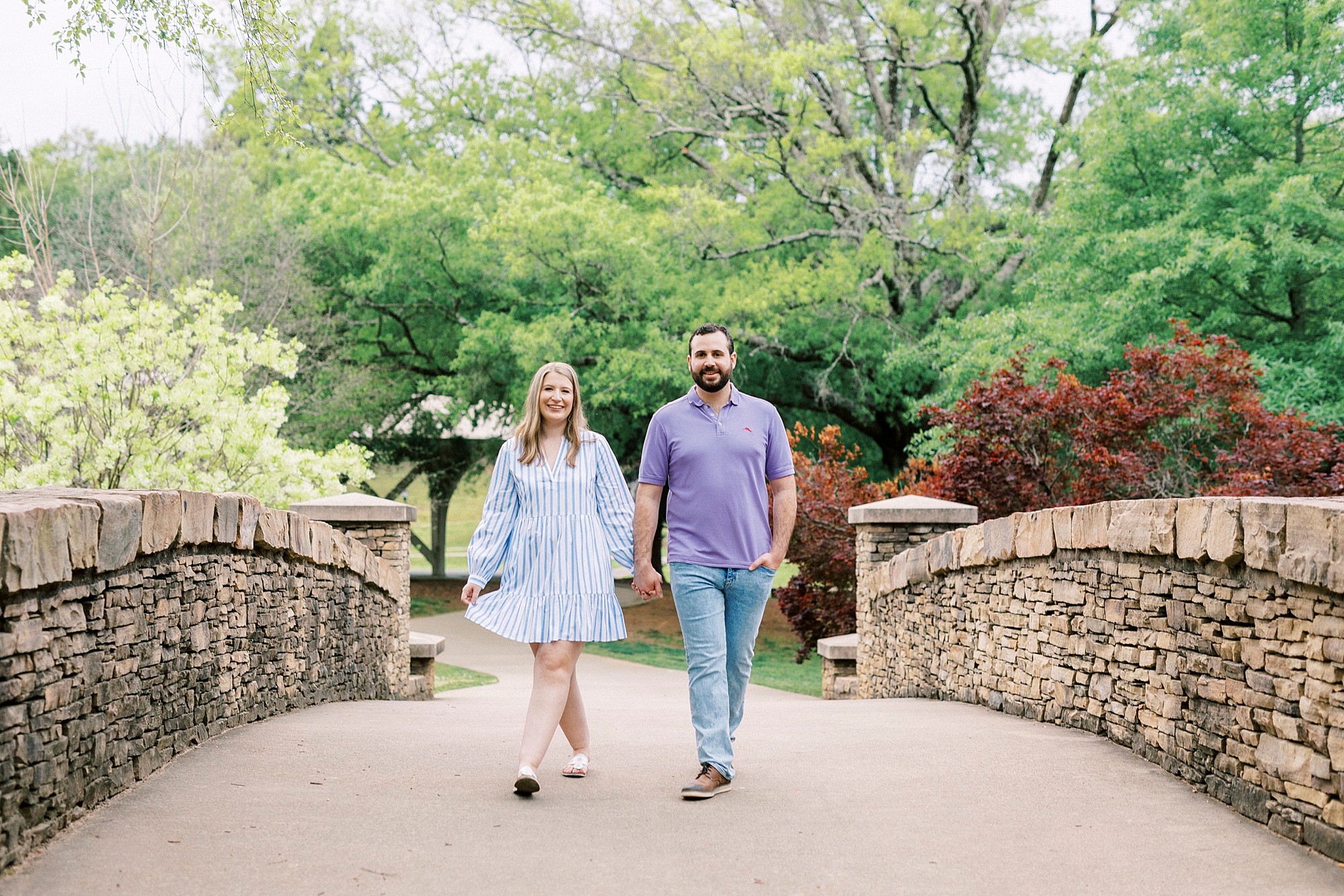bride and groom hold and walking over stone bridge at Freedom Park