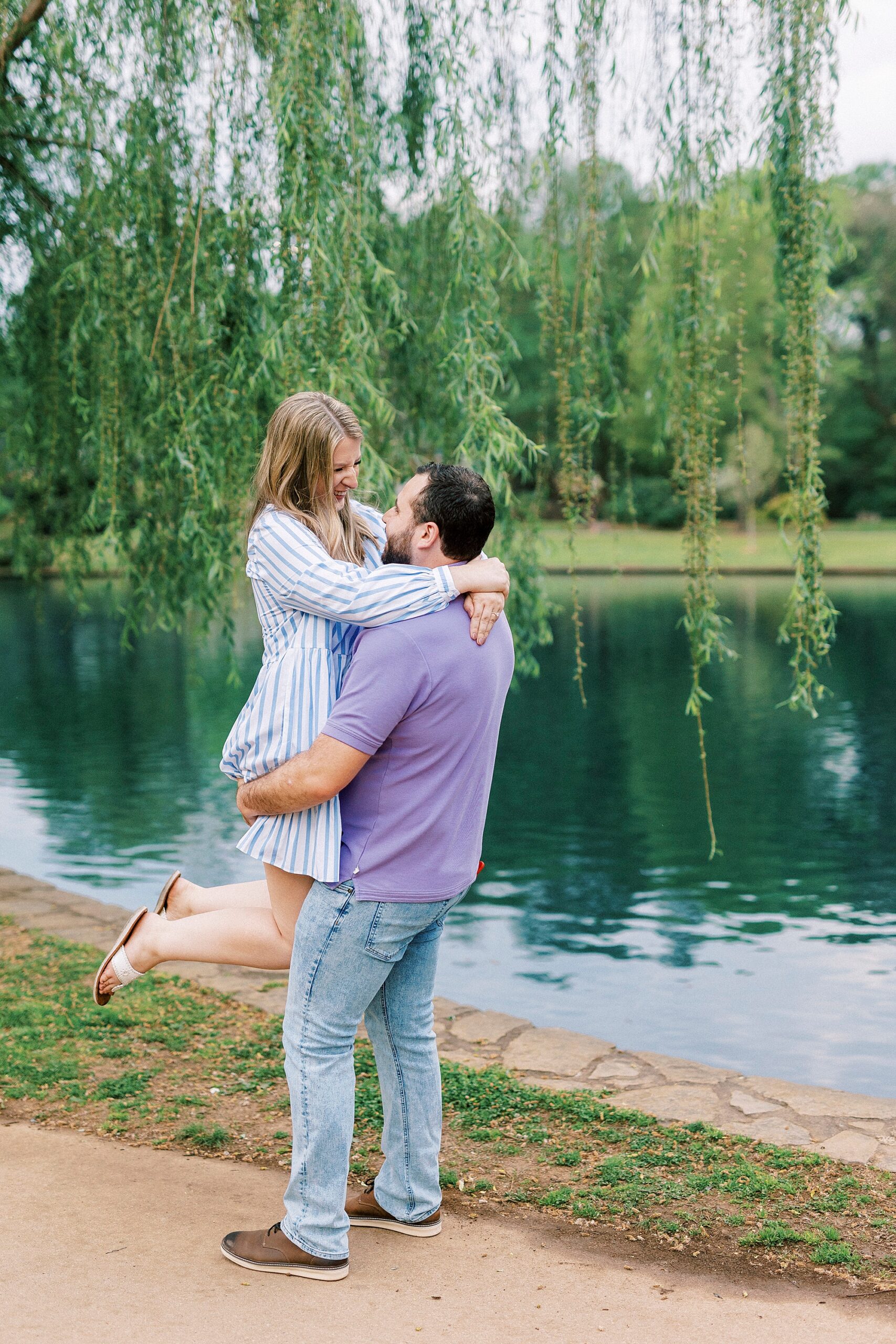 groom lifts up bride under weeping willow at Freedom Park