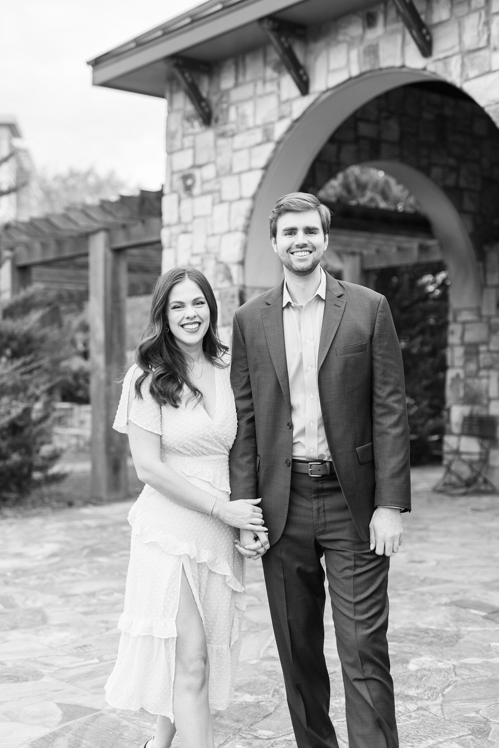 couple holds hands near stone arbor during Midtown Park engagement portraits