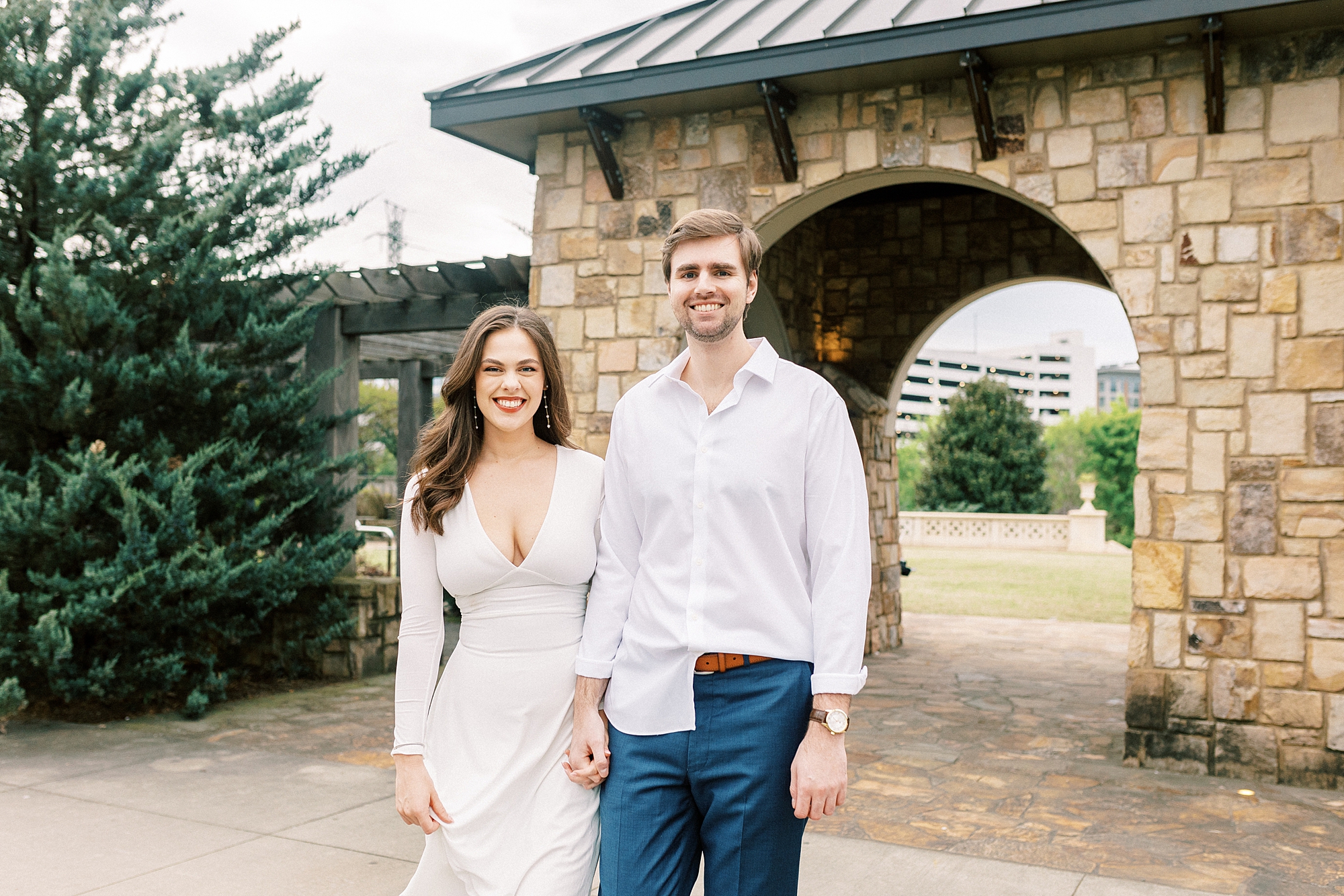 couple holds hands by stone wall at Midtown Park