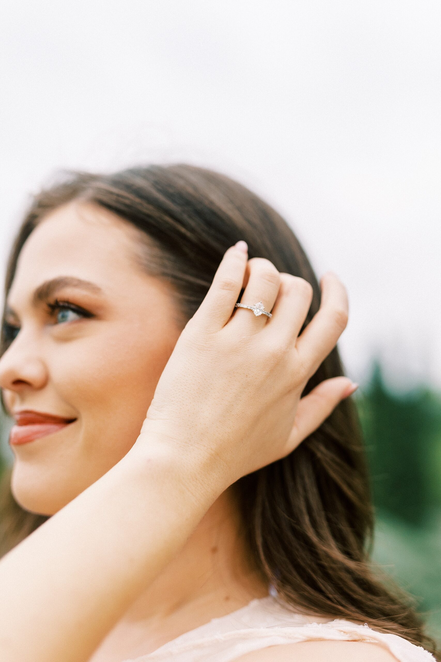 woman pushes hair behind ear with engagement ring at Midtown Park engagement session 