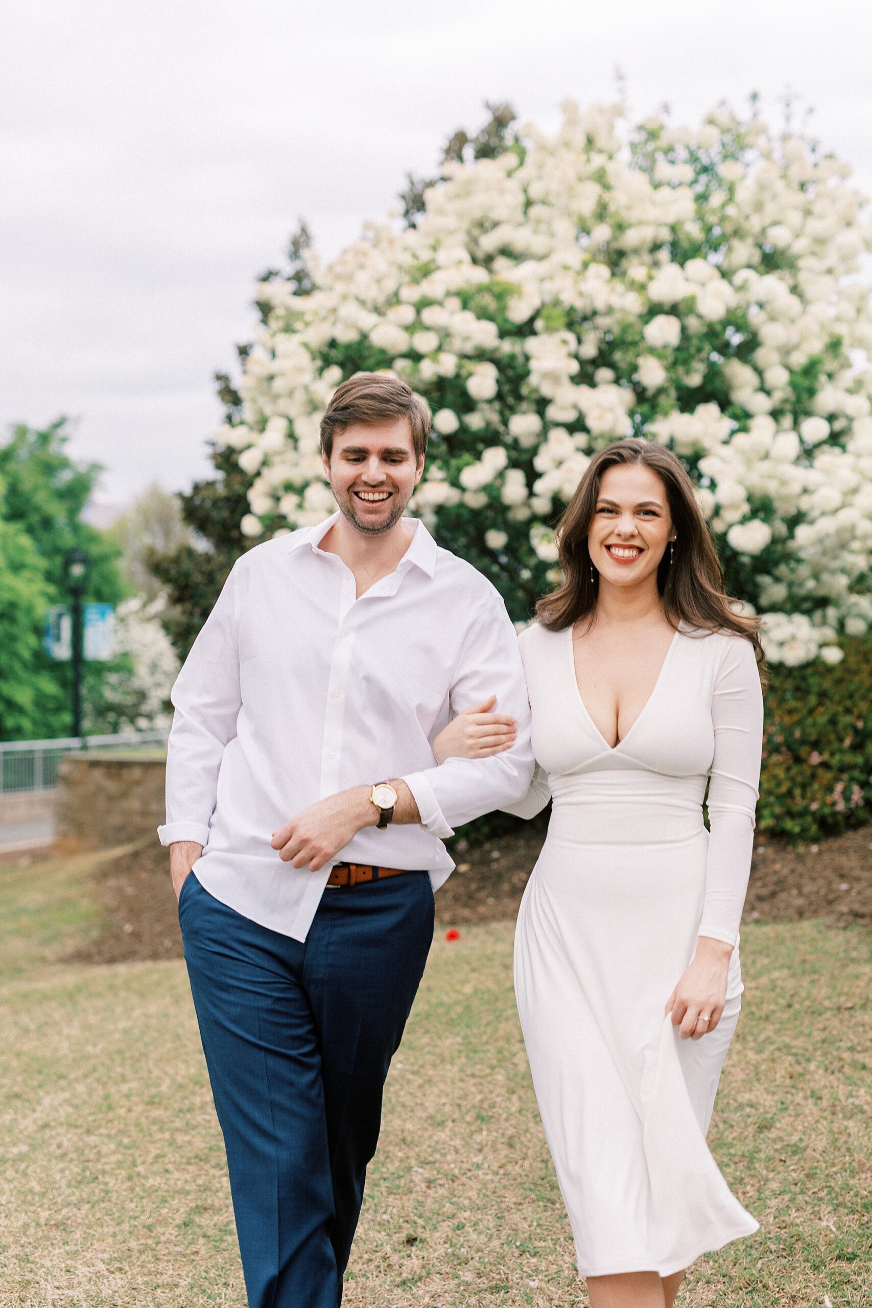man walks with woman through park during Midtown Park engagement session 