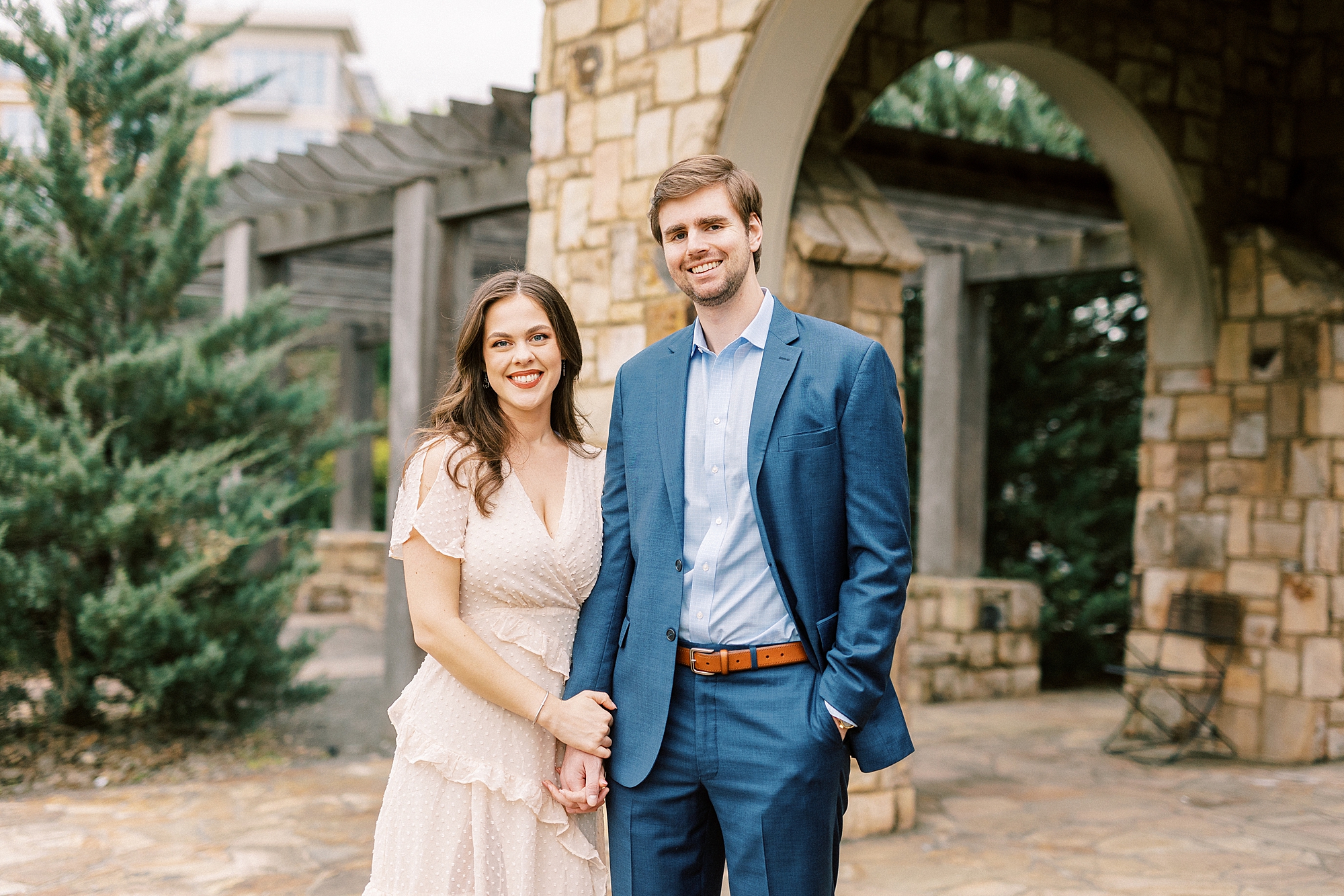engaged couple holds hands near stone arbor during Midtown Park engagement portraits
