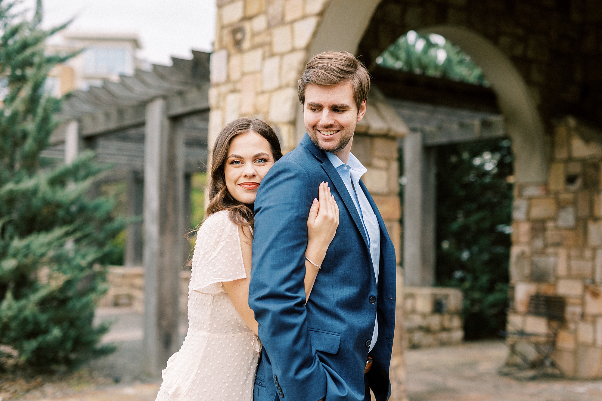 woman hugs man from behind in front of stone arbor at Midtown Park