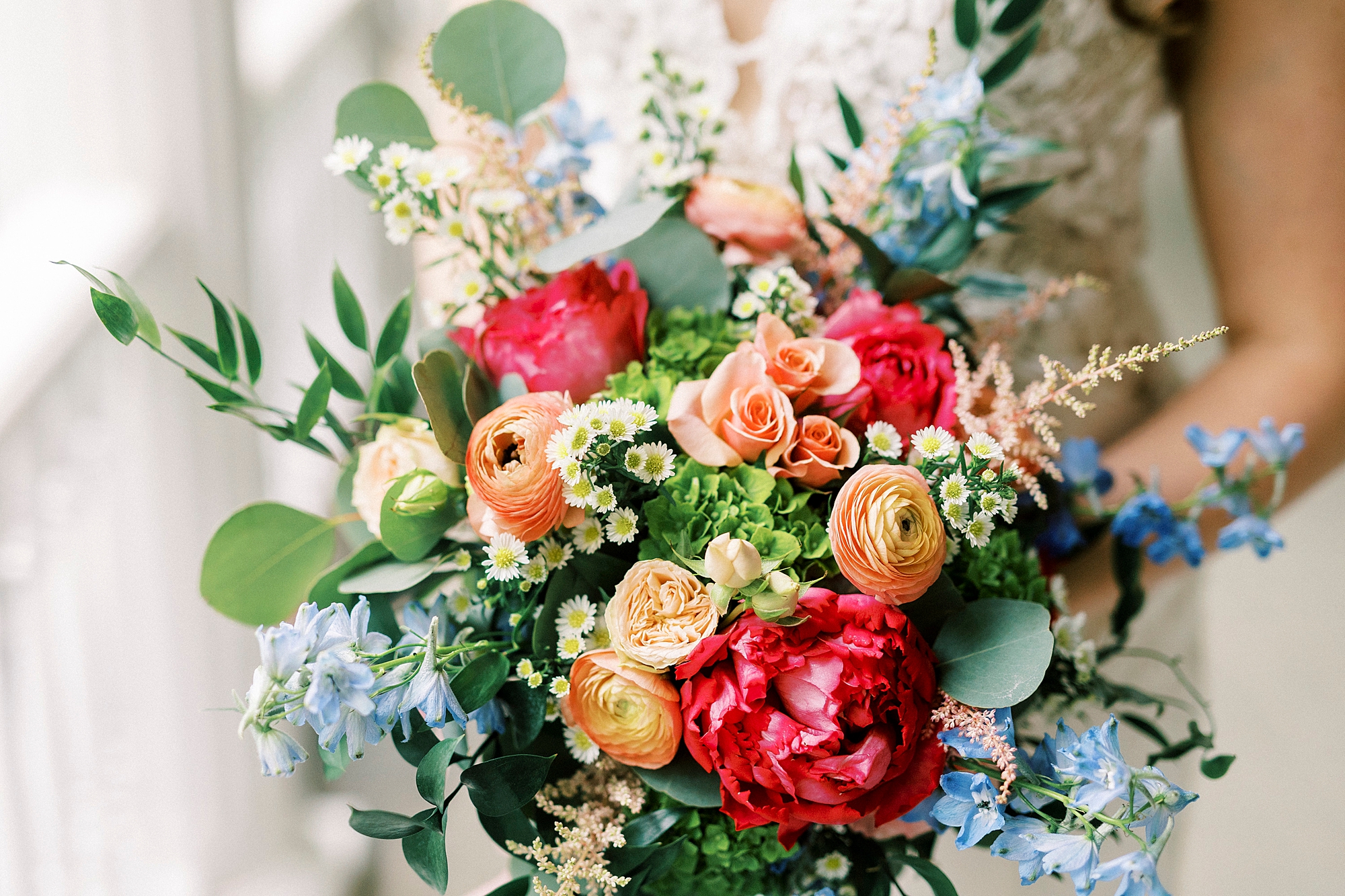 bride holds bouquet of pink and orange flowers on porch at The Saratoga Springs