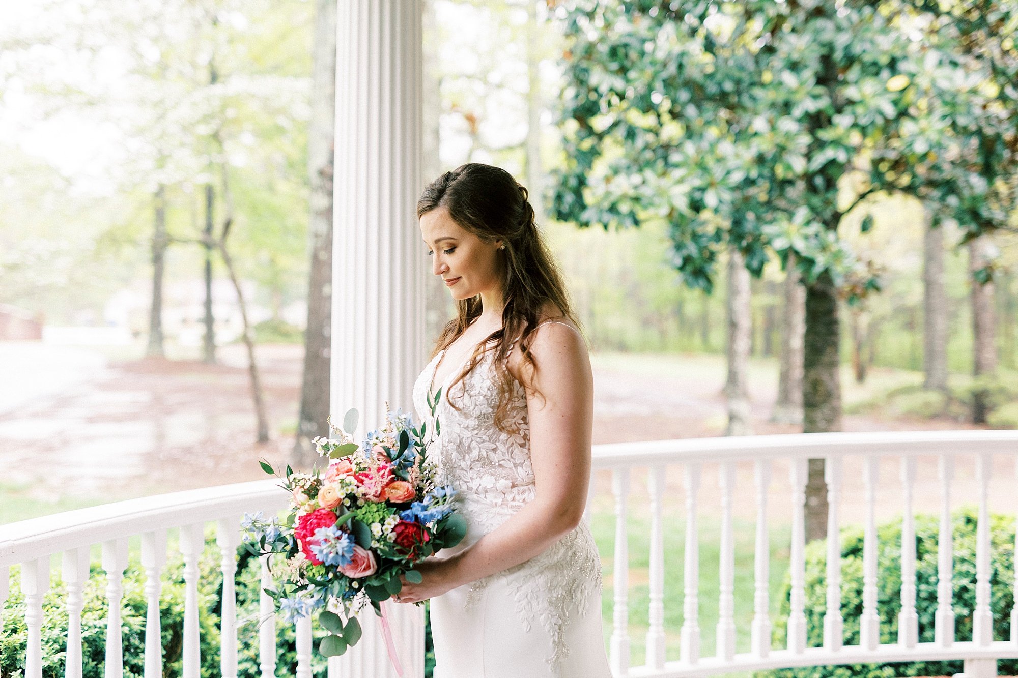 bride looks down at pink and peach bouquet on porch at The Saratoga Springs
