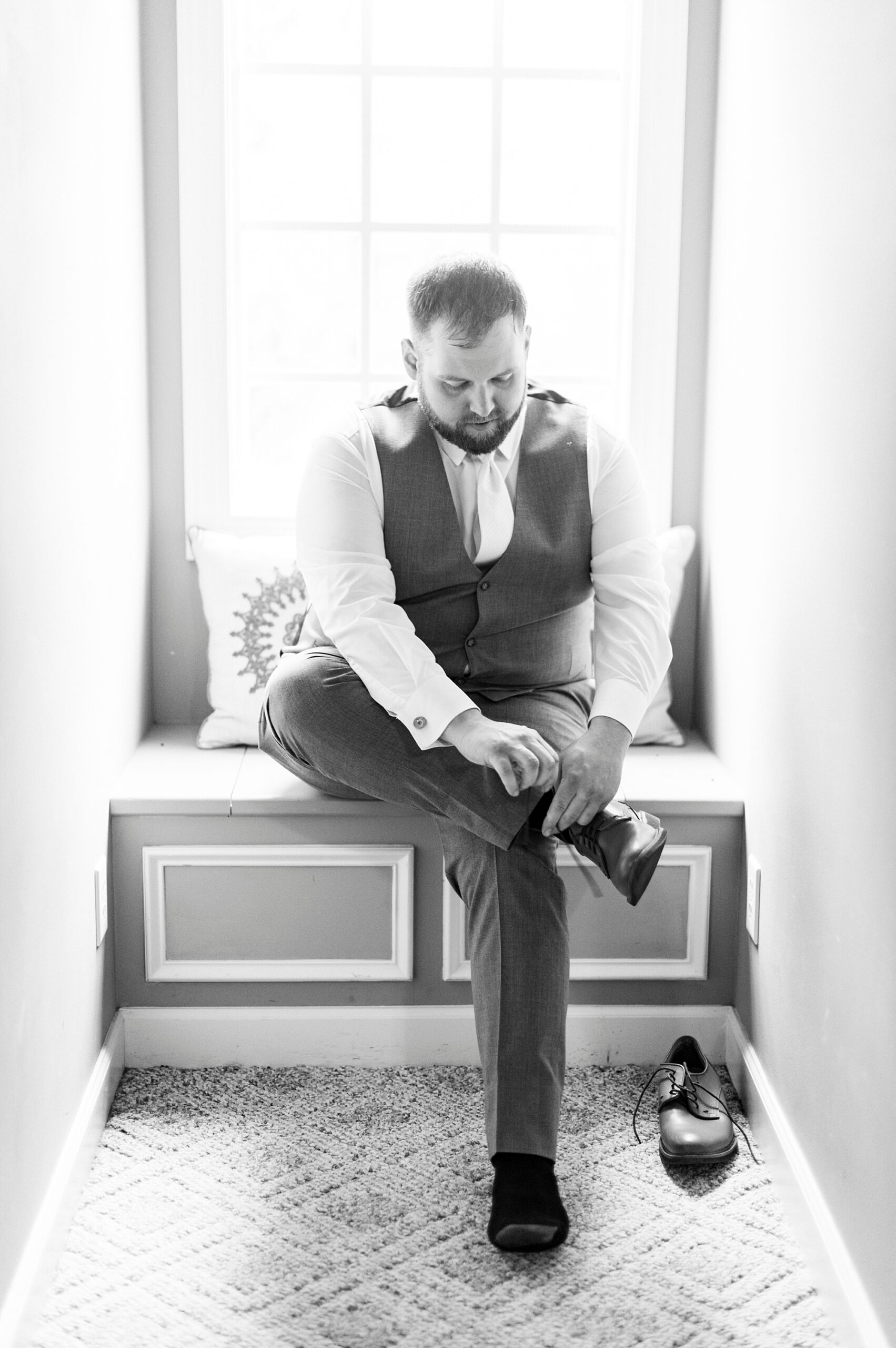 groom sits on window seat adjust shoes at The Saratoga Springs