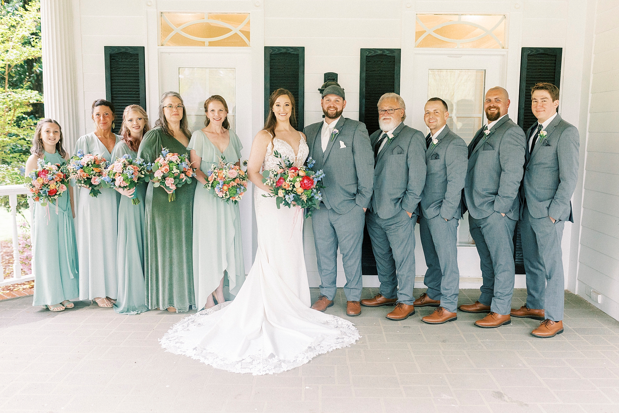 bride and groom pose with wedding party on the porch at The Saratoga Springs