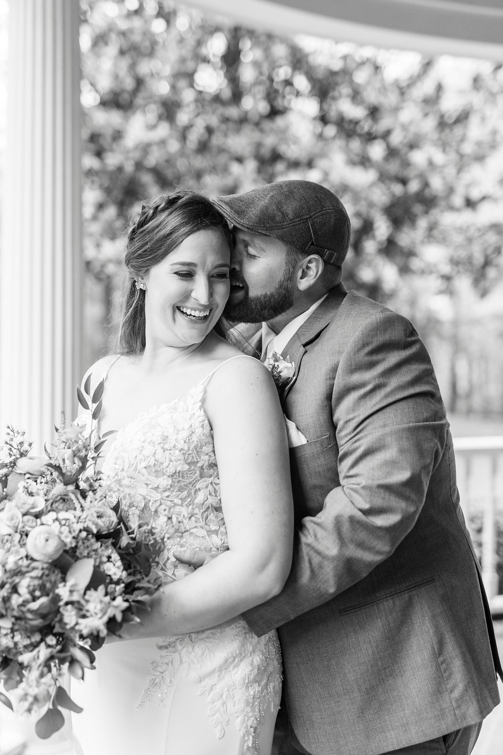 groom kisses bride's cheek from behind on porch at The Saratoga Springs