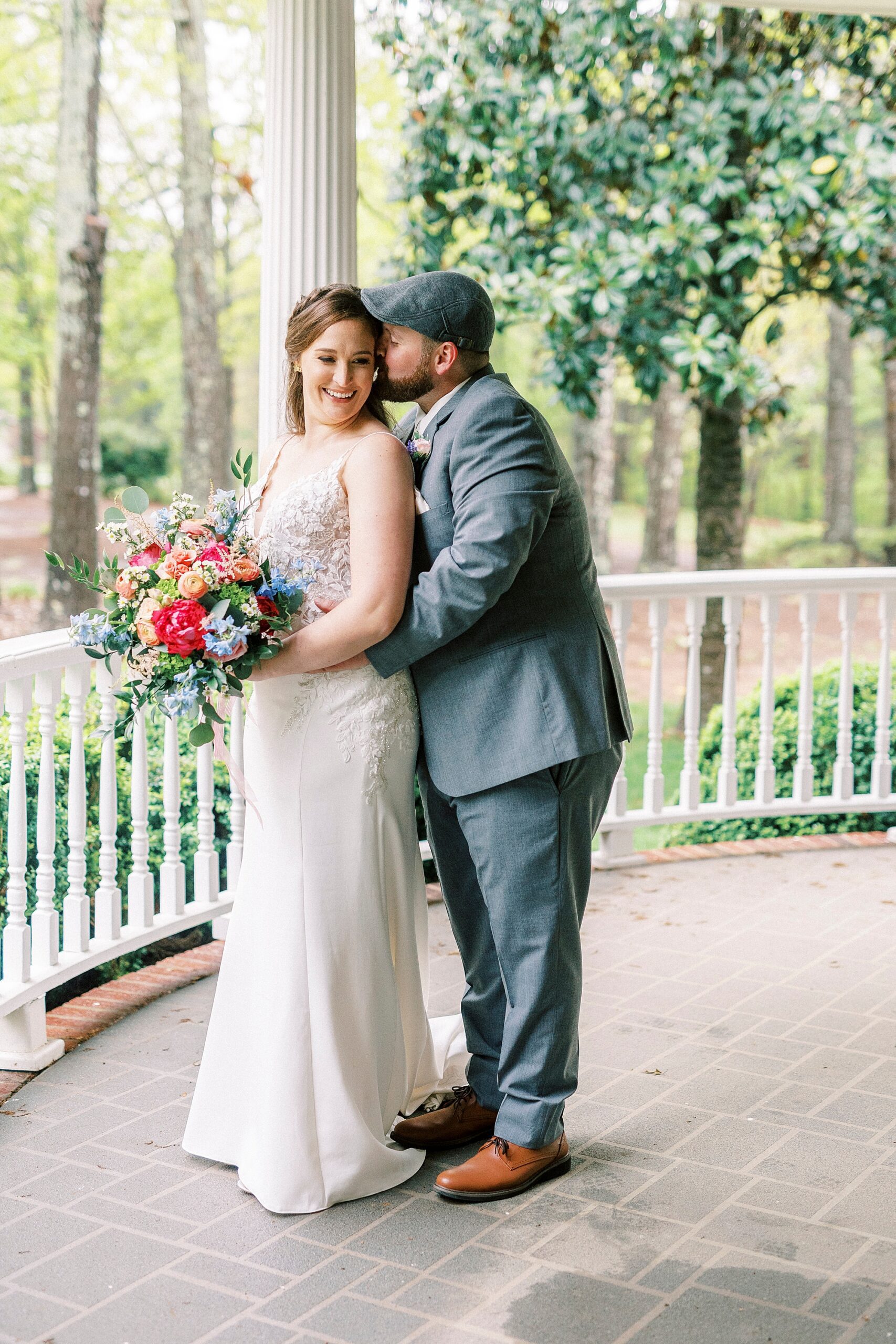 groom kisses bride's cheek hugging her from behind during wedding photos in Charlotte NC