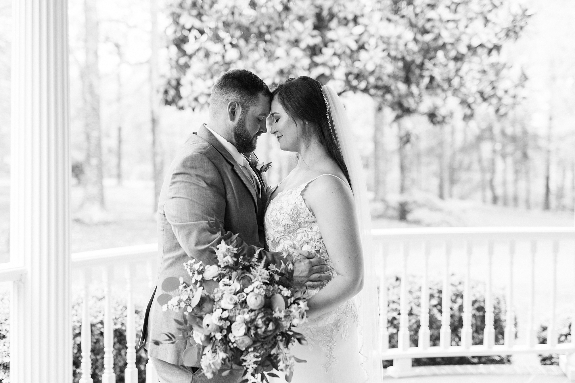 newlyweds lean heads together on porch at The Saratoga Springs