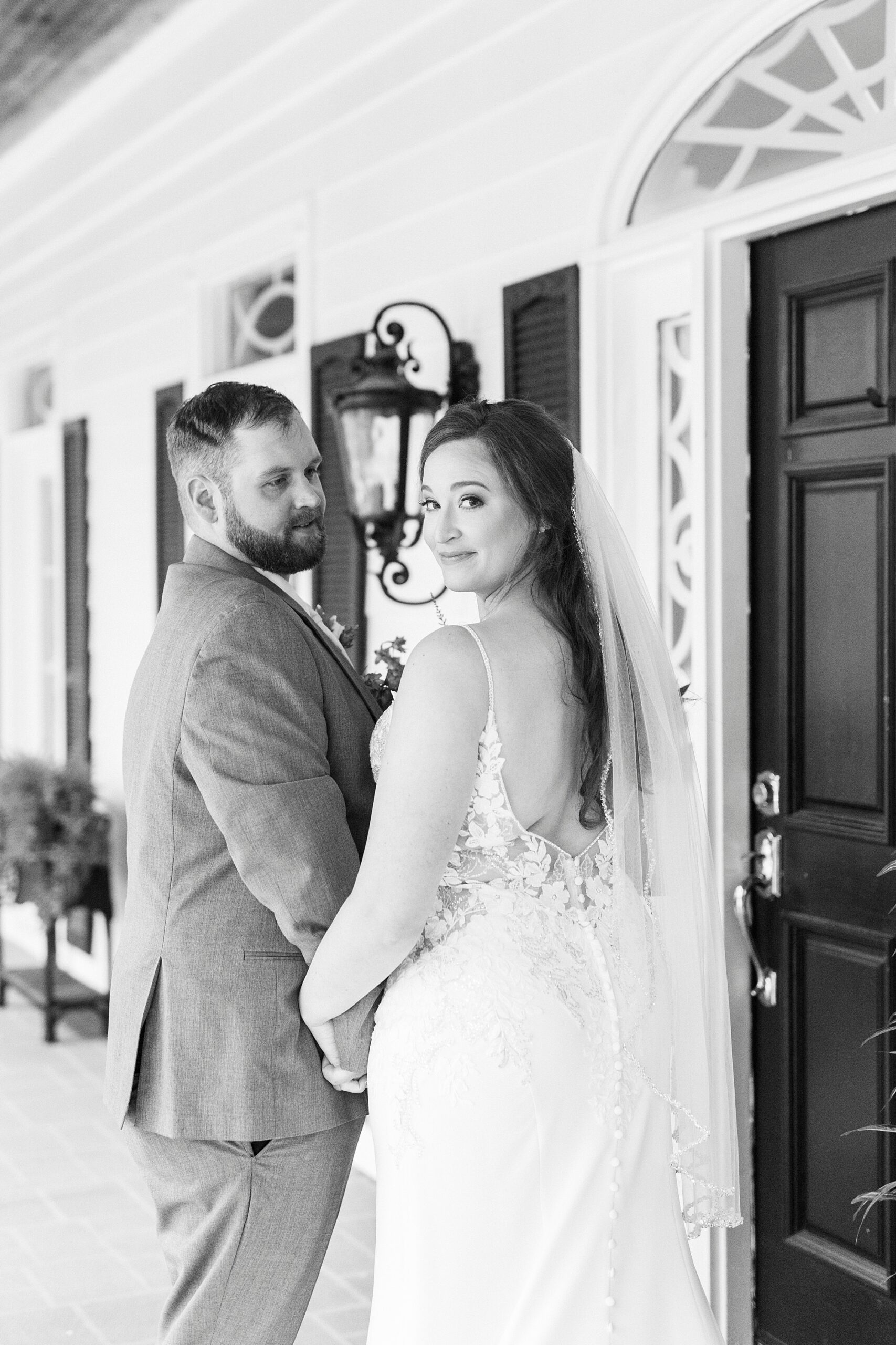 bride and groom hold hands walking towards door looking over shoulders 