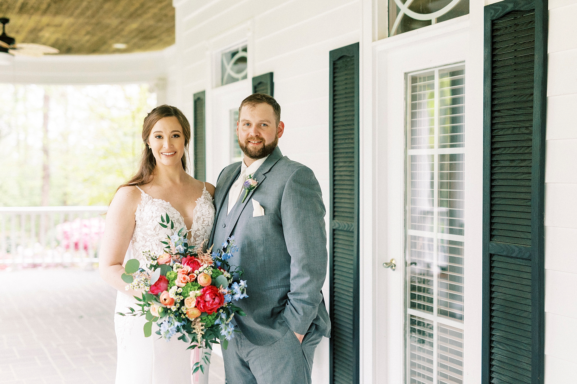 newlyweds hug by green and white windows at The Saratoga Springs
