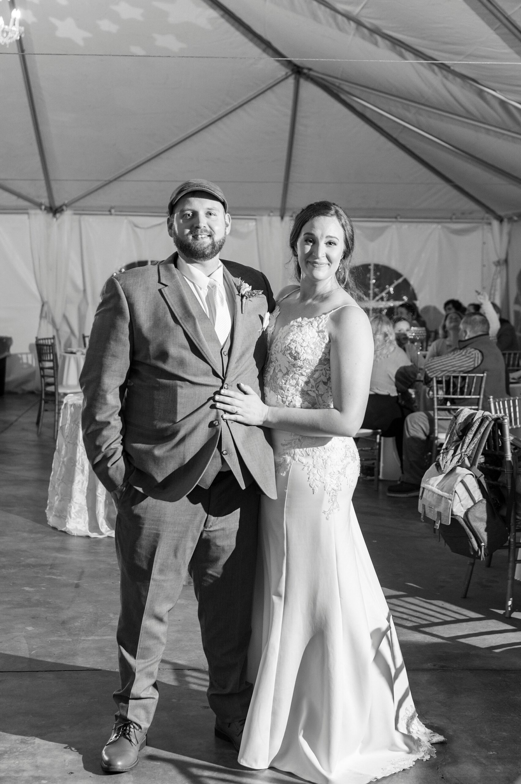 bride and groom stand hugging under tent 