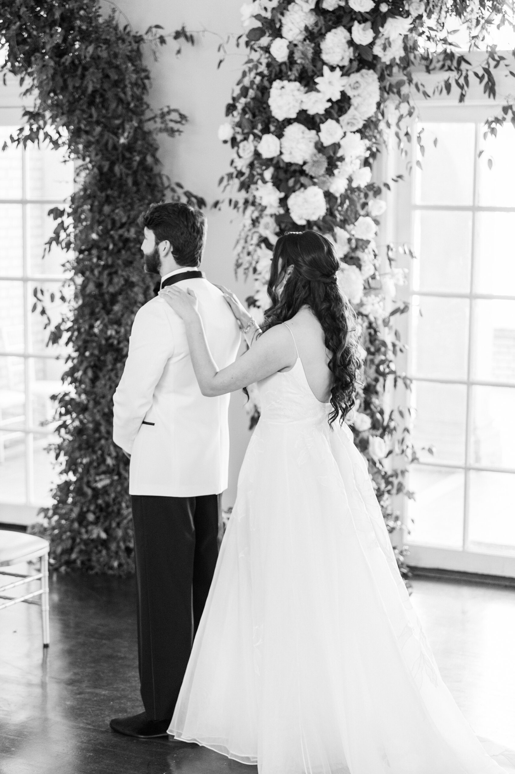 bride taps groom's shoulder in white tux 