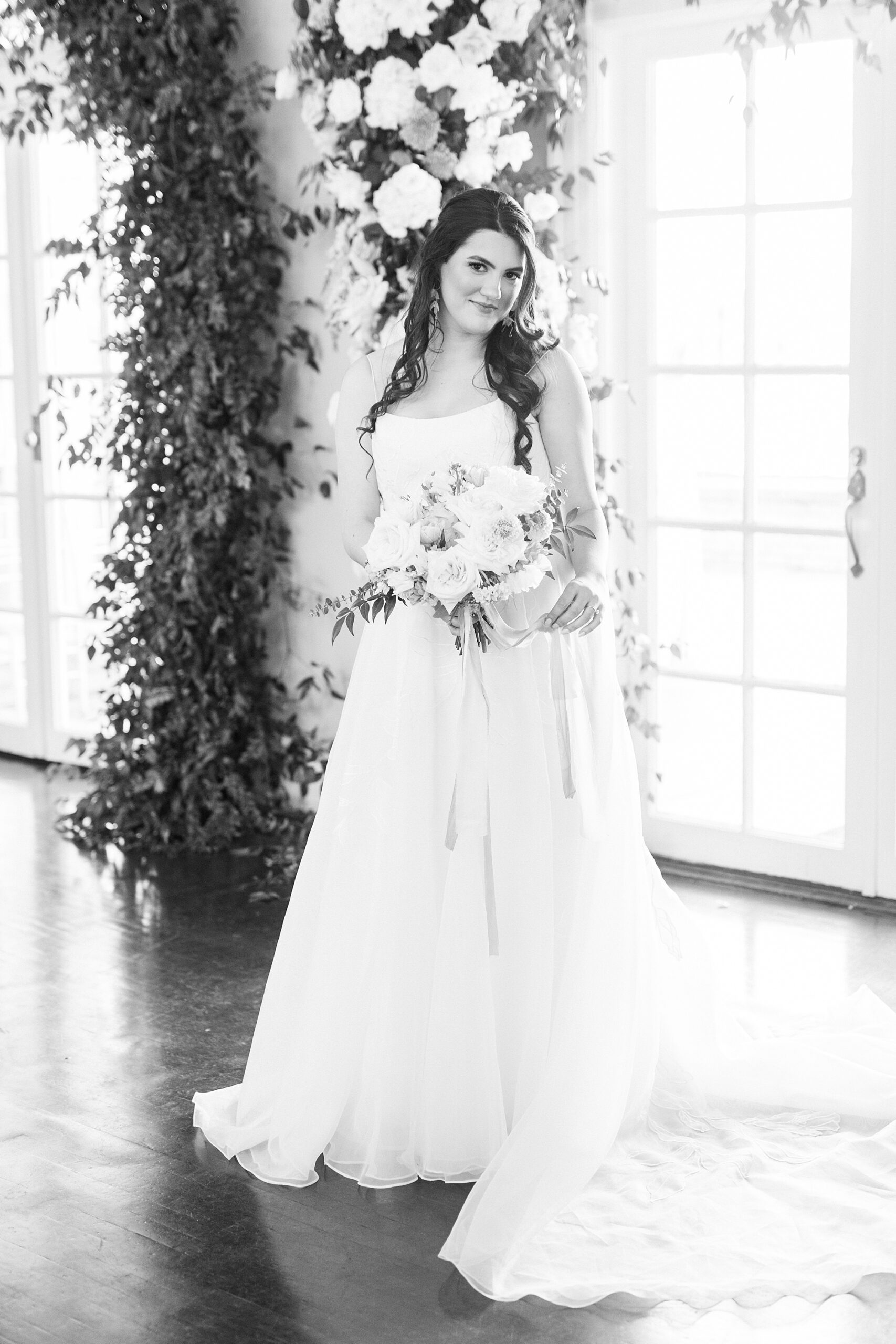 bride holds bouquet of ivory flowers under floral arbor at Separk Mansion