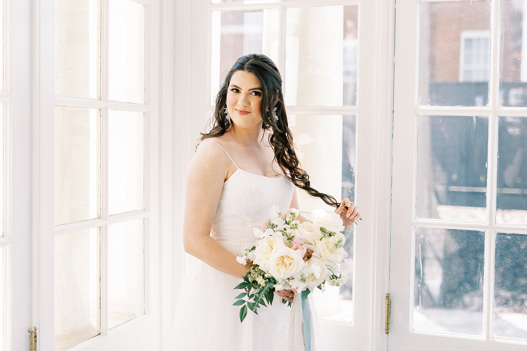 bride holds bouquet of ivory and pink flowers inside patio room at Separk Mansion