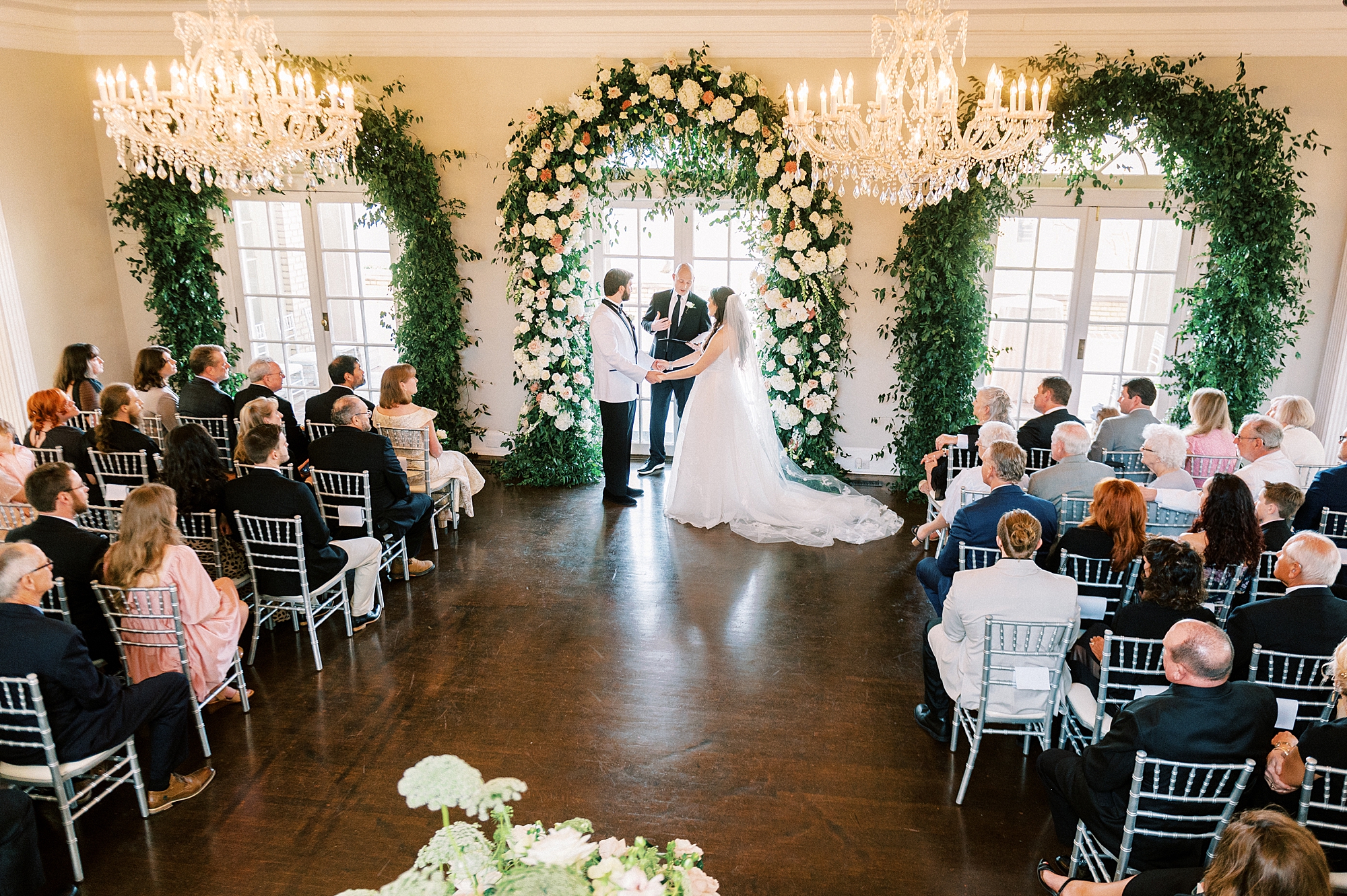 newlyweds hold hands during wedding ceremony inside Separk Mansion