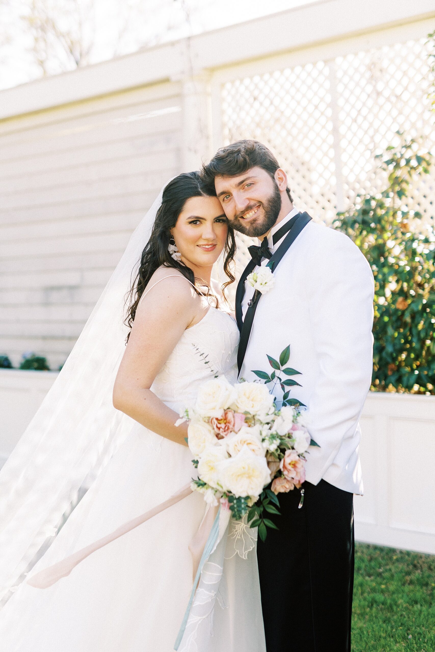 bride and groom hug in front of white wall at Separk Mansion