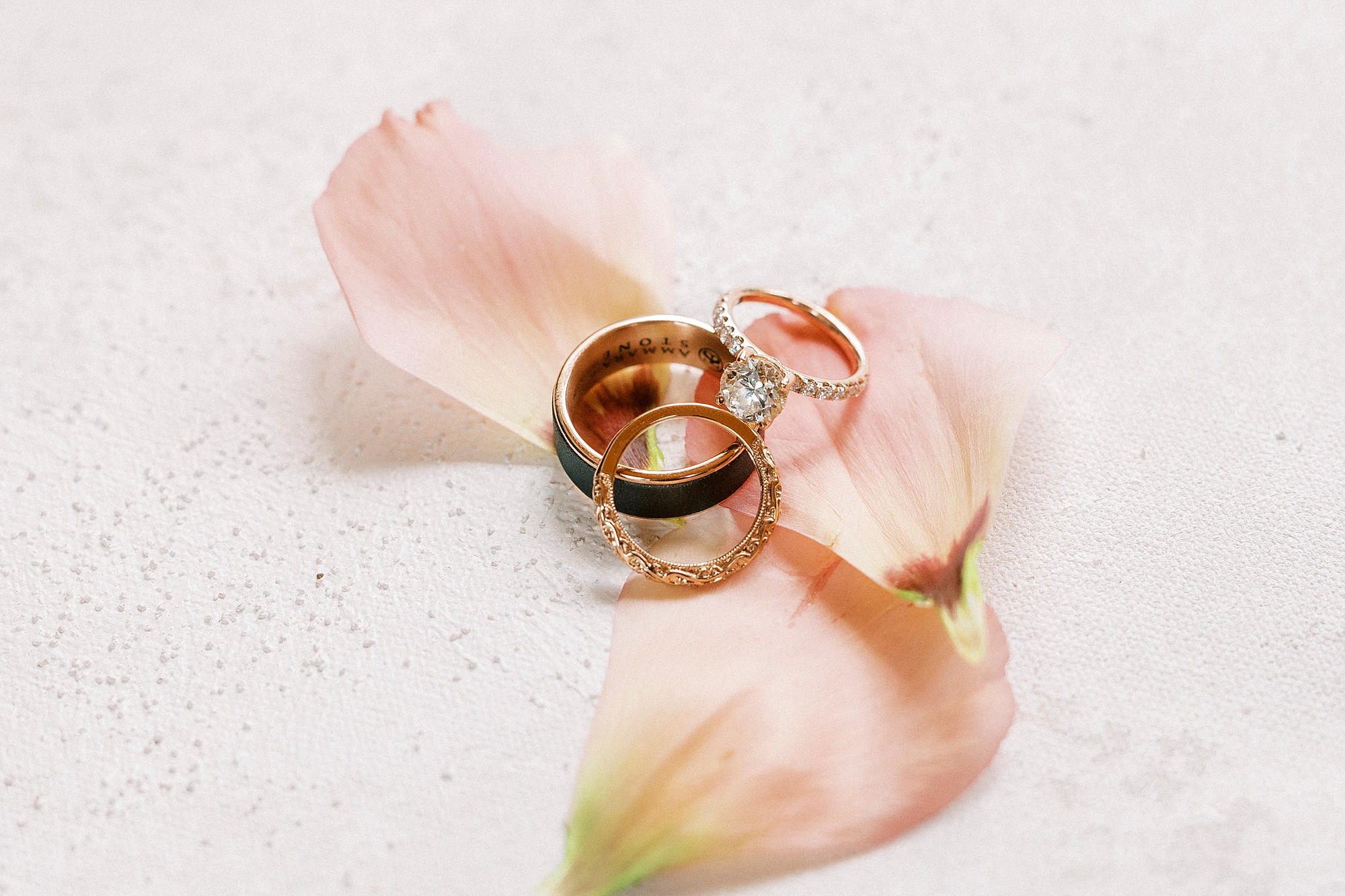 rose gold wedding bands rest on pink petals 