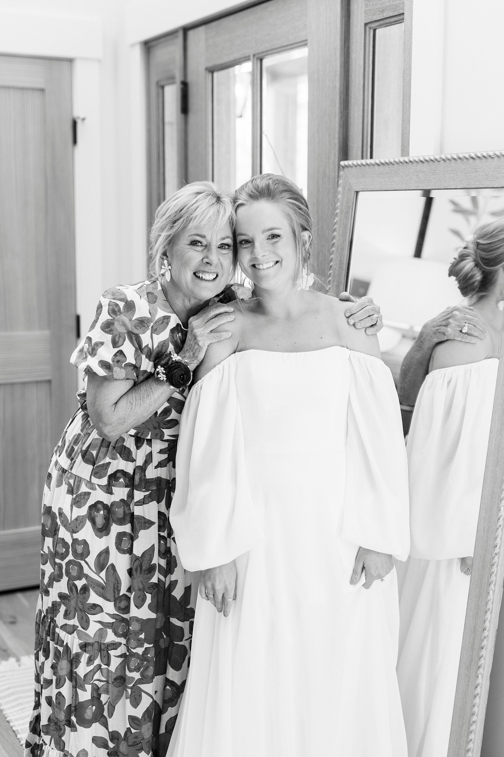 bride and mom hug by mirror in bride's home