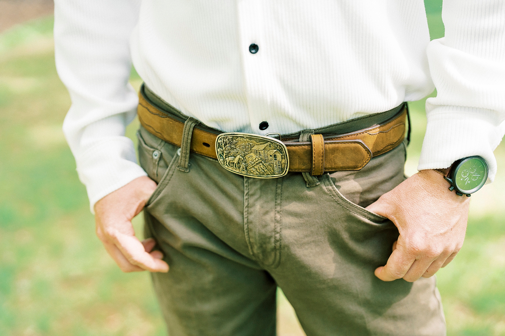 groom stands with hands in pockets of jeans 