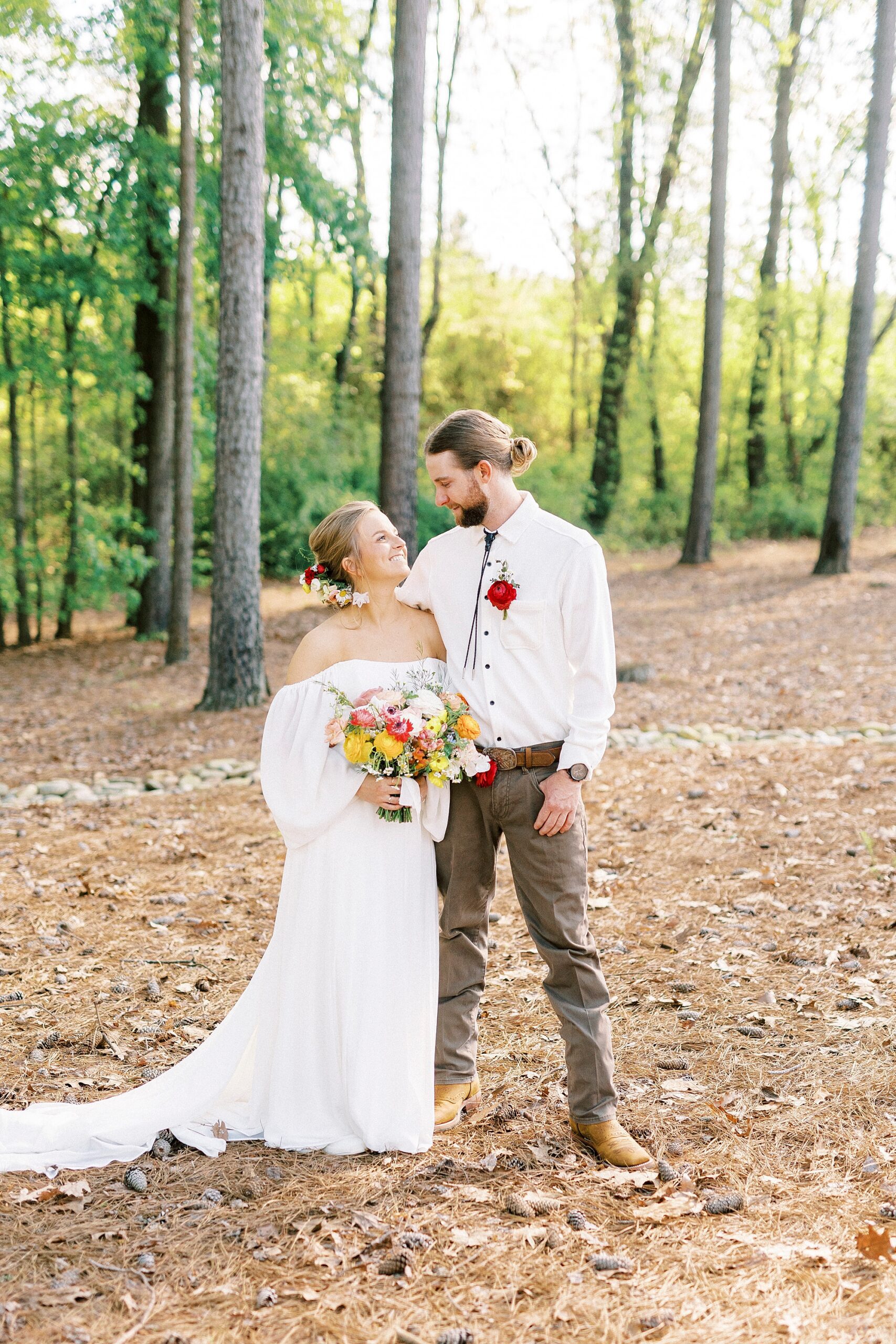 newlyweds smile at each other on lawn of home