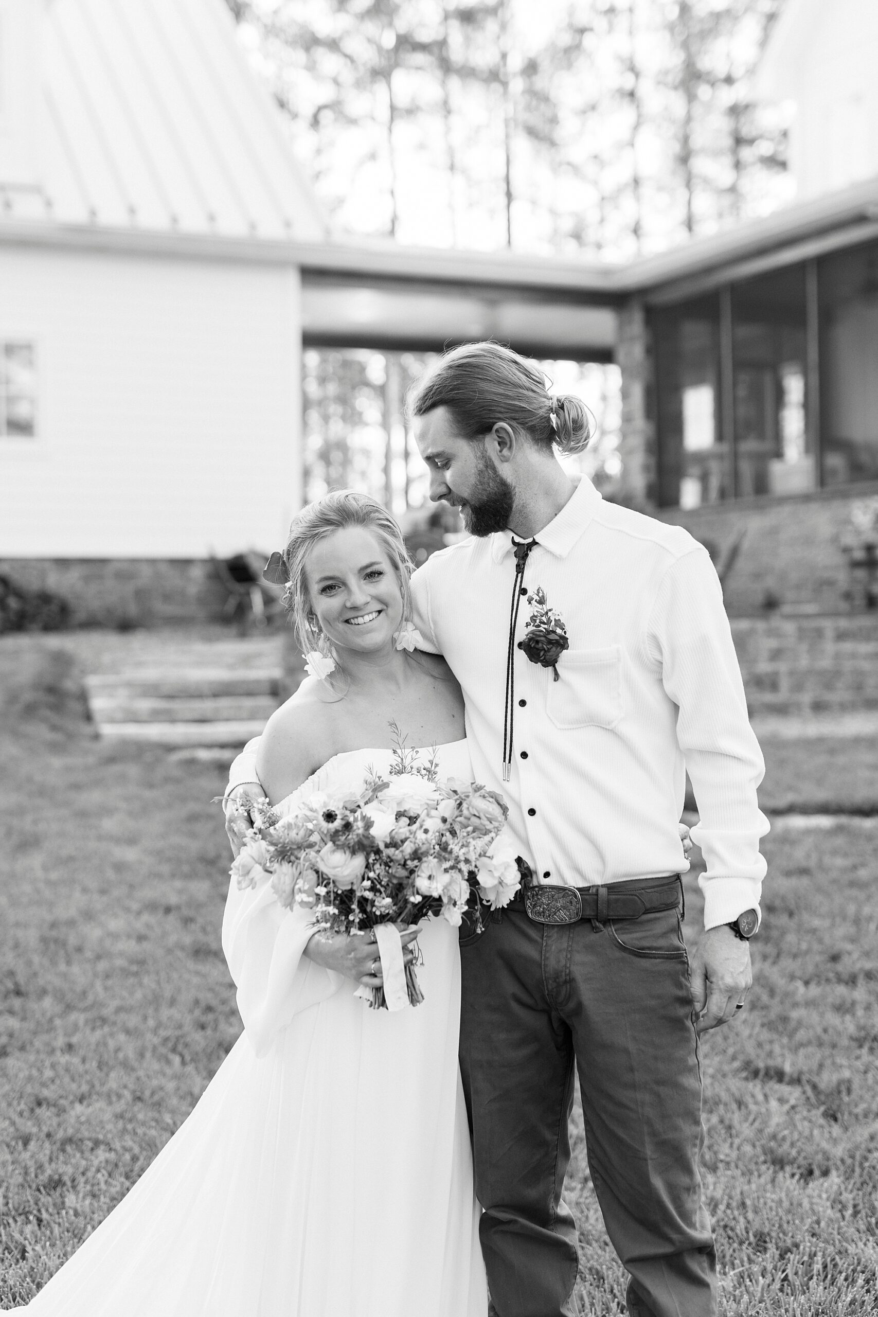groom smiles looking at bride hugging her to his hip