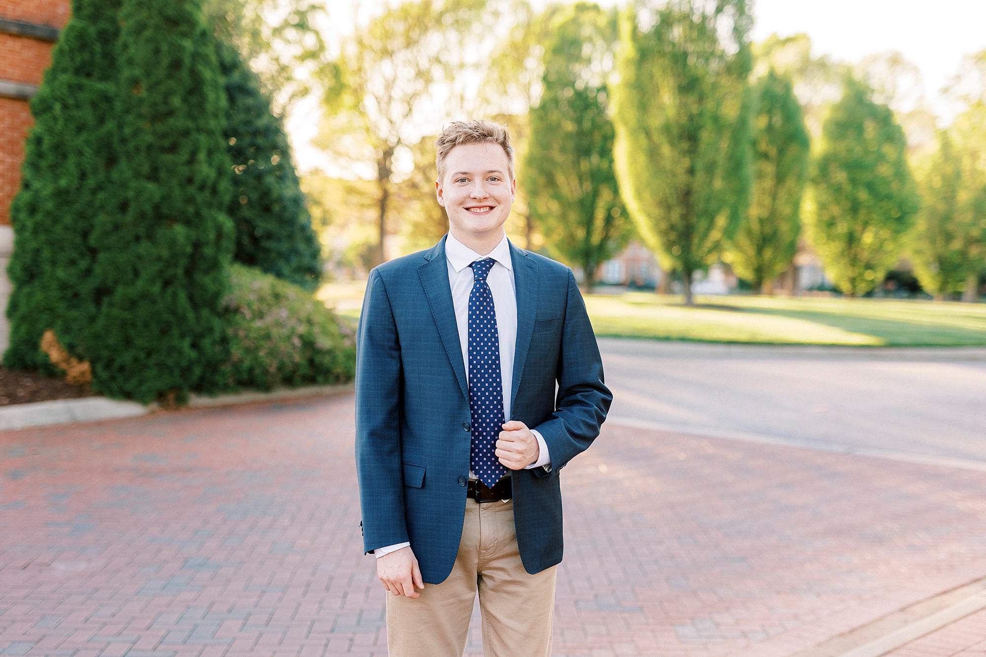 groom in navy suit jacket stands on campus at UNC Charlotte