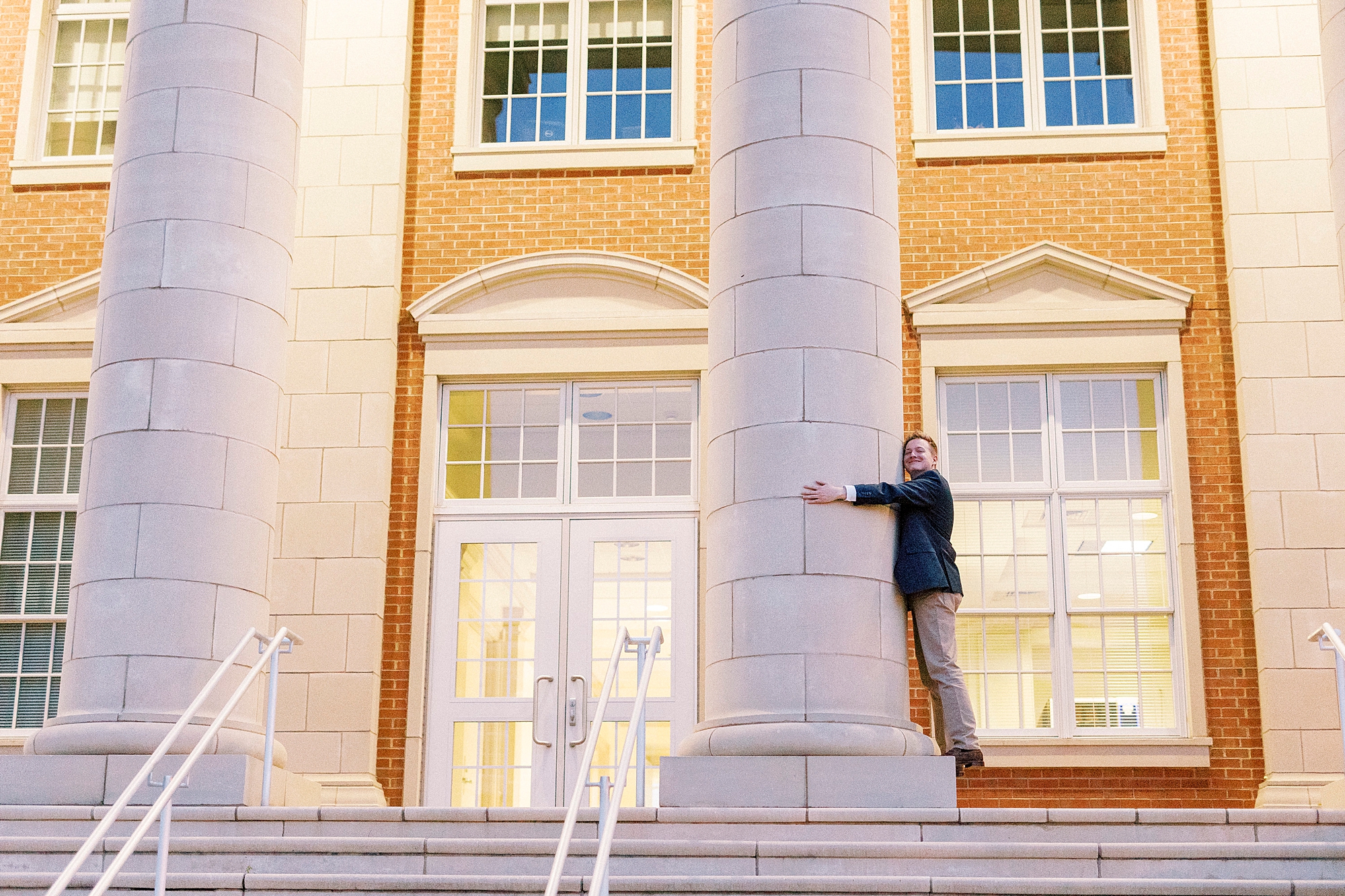 senior guy hugs pillar of building at UNC Charlotte