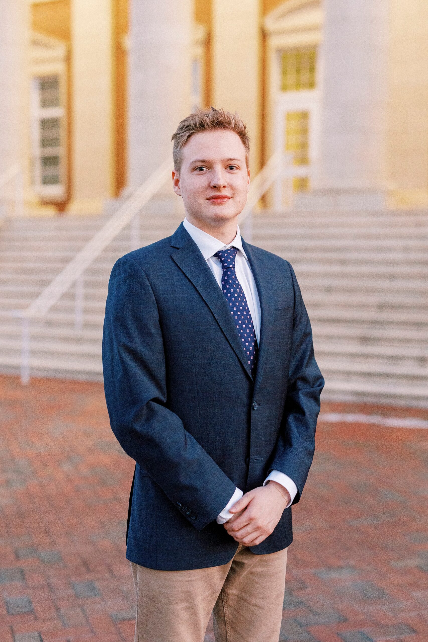 senior stands in navy blazer outside buildings at UNC Charlotte