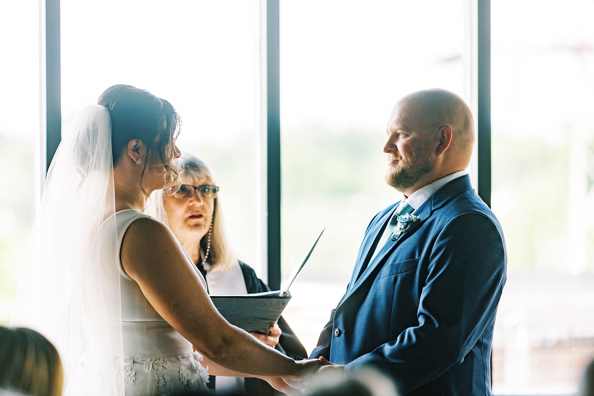 bride and groom hold hands by window at the Terrace at Cedar Hill