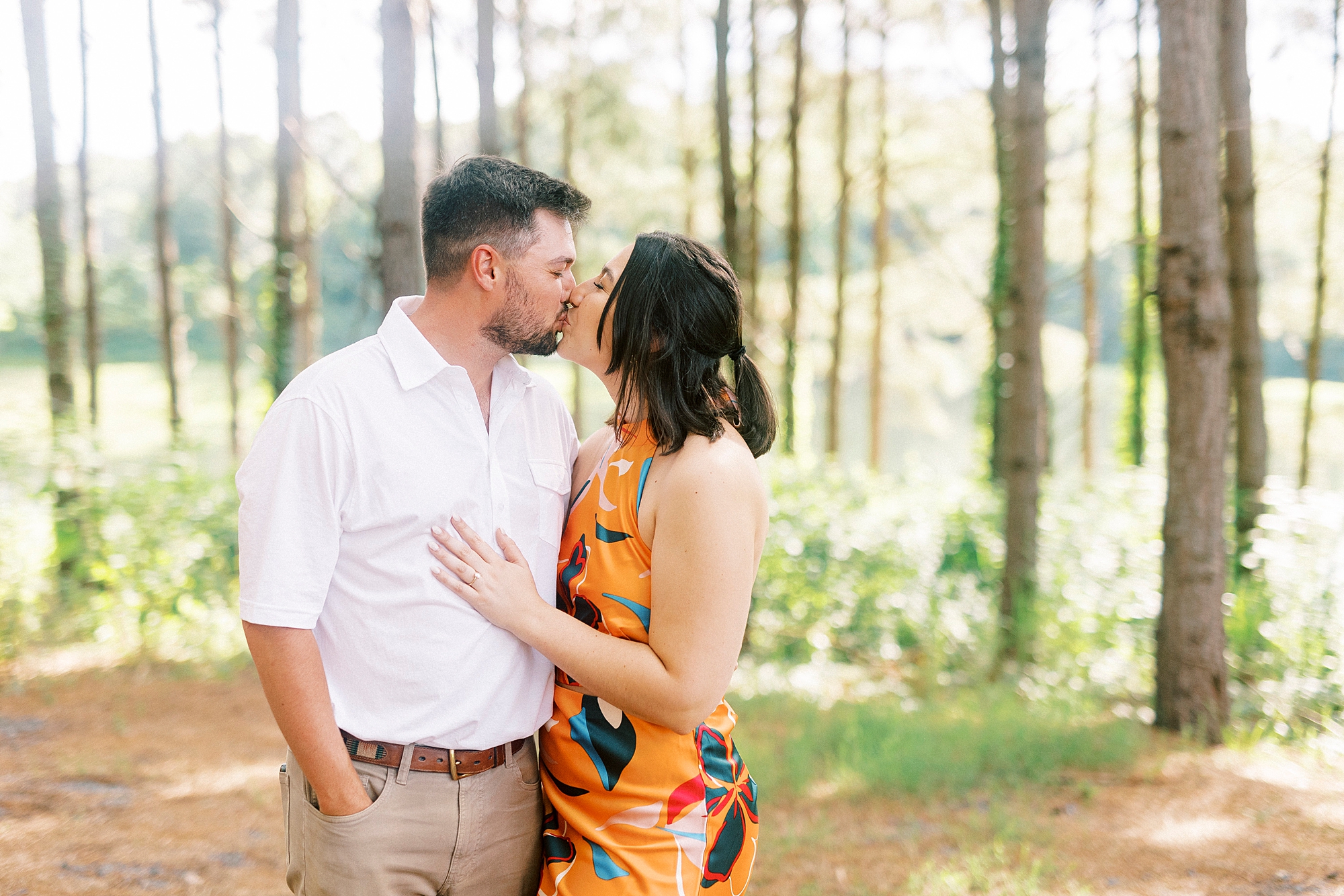 couple kisses along wood line after Albemarle proposal on the lake