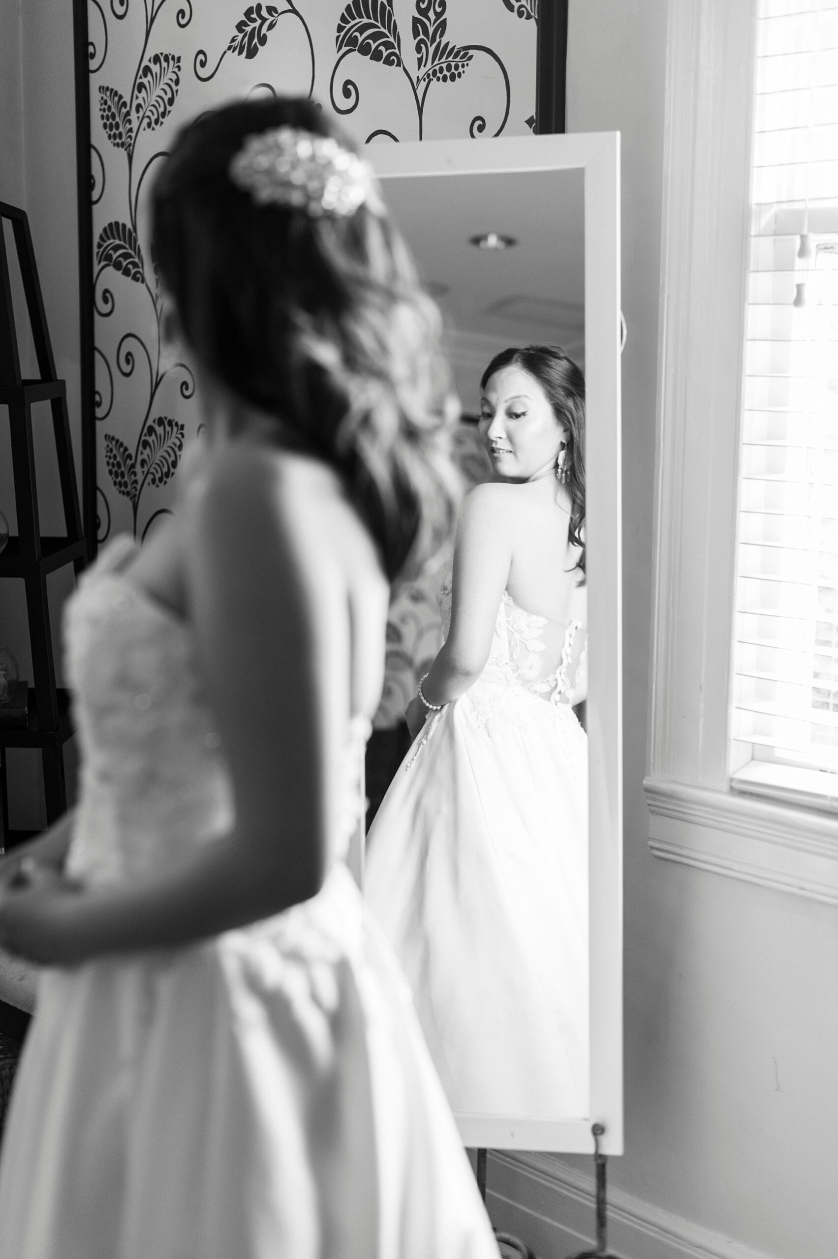 bride looks over shoulder in self in mirror in suite at The Spring House