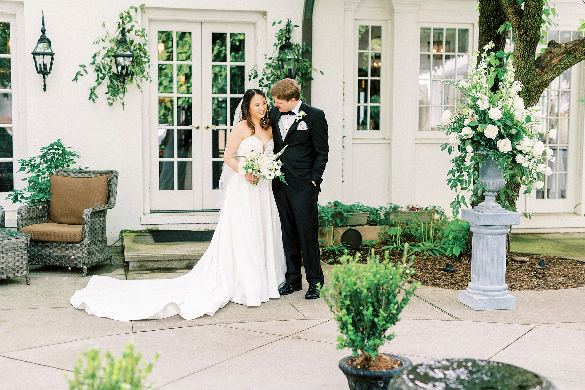 groom hugs bride outside white French doors during first look at The Spring House