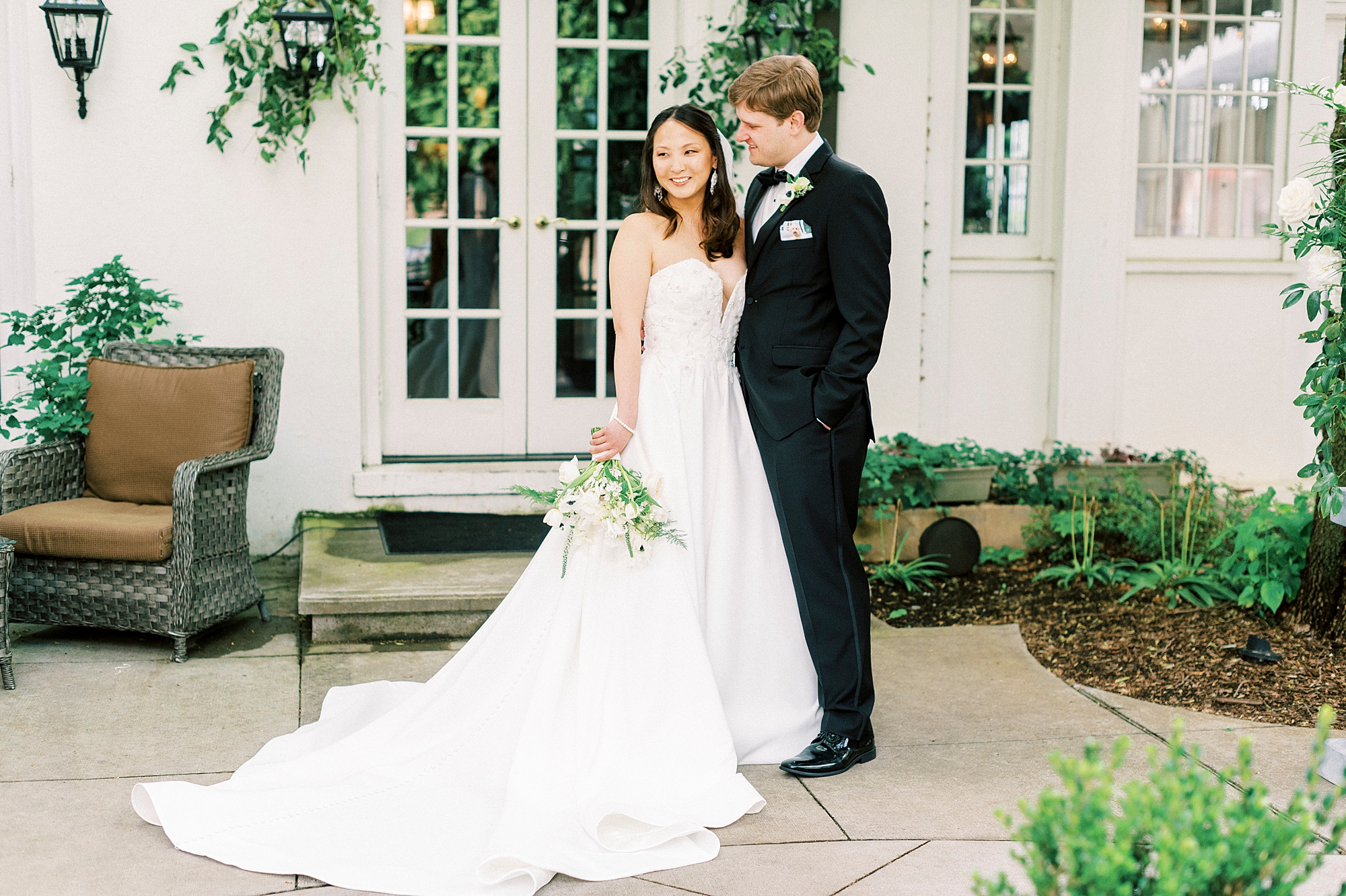 groom hugs bride to him looking at her outside The Spring House